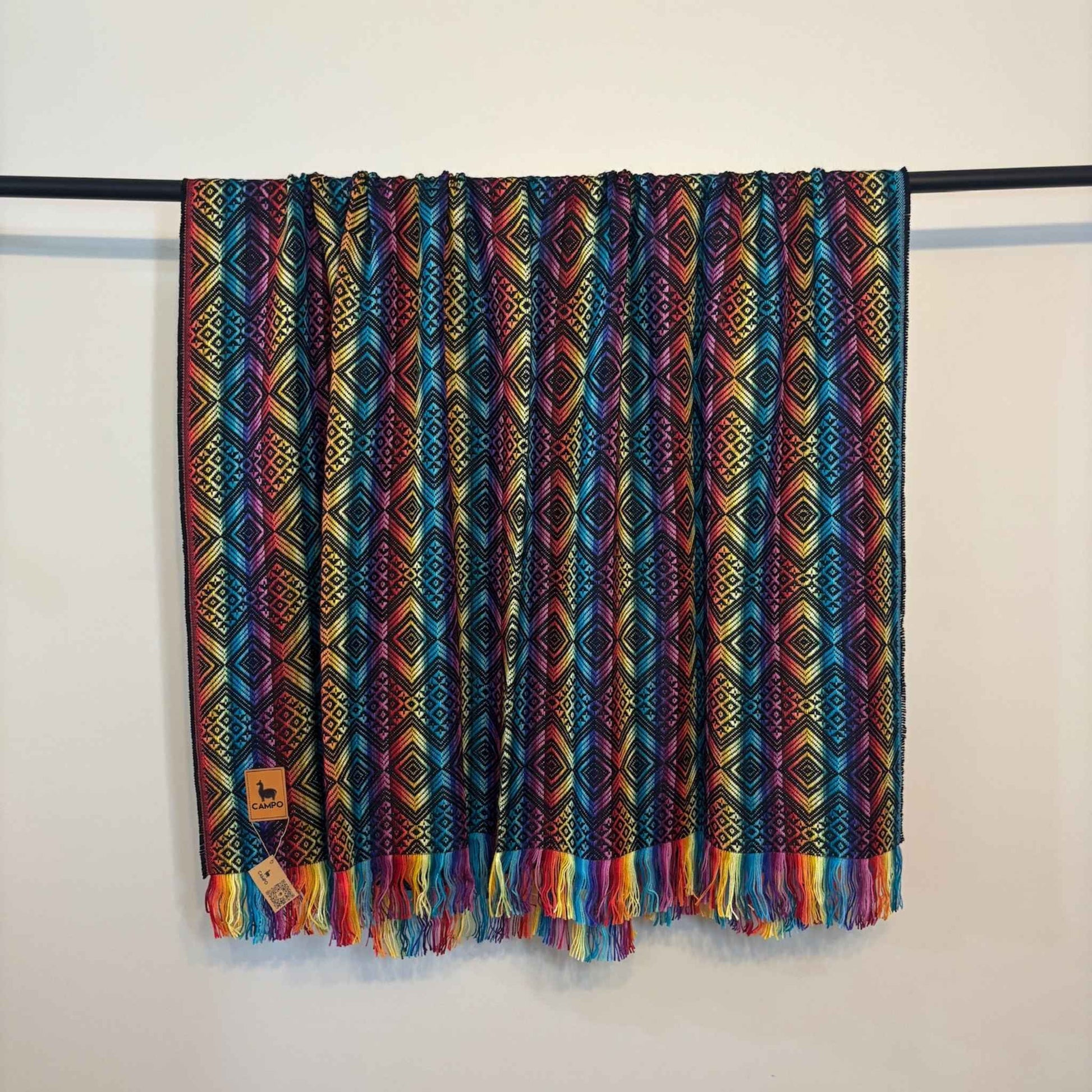 Black rainbow patterned blanket with fringes on a white background