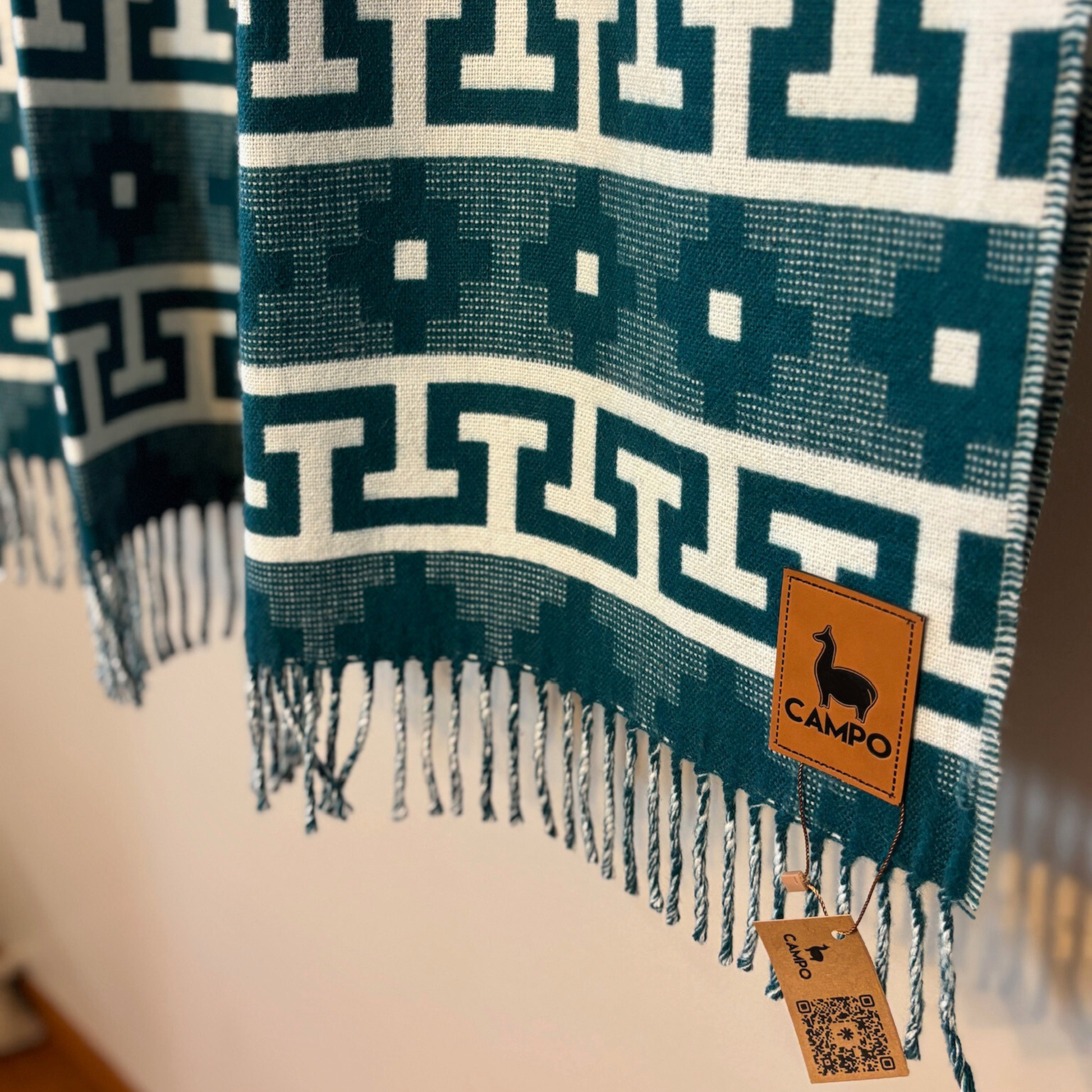 Forest green patterned blanket with fringes and a 'Campo' brand tag.