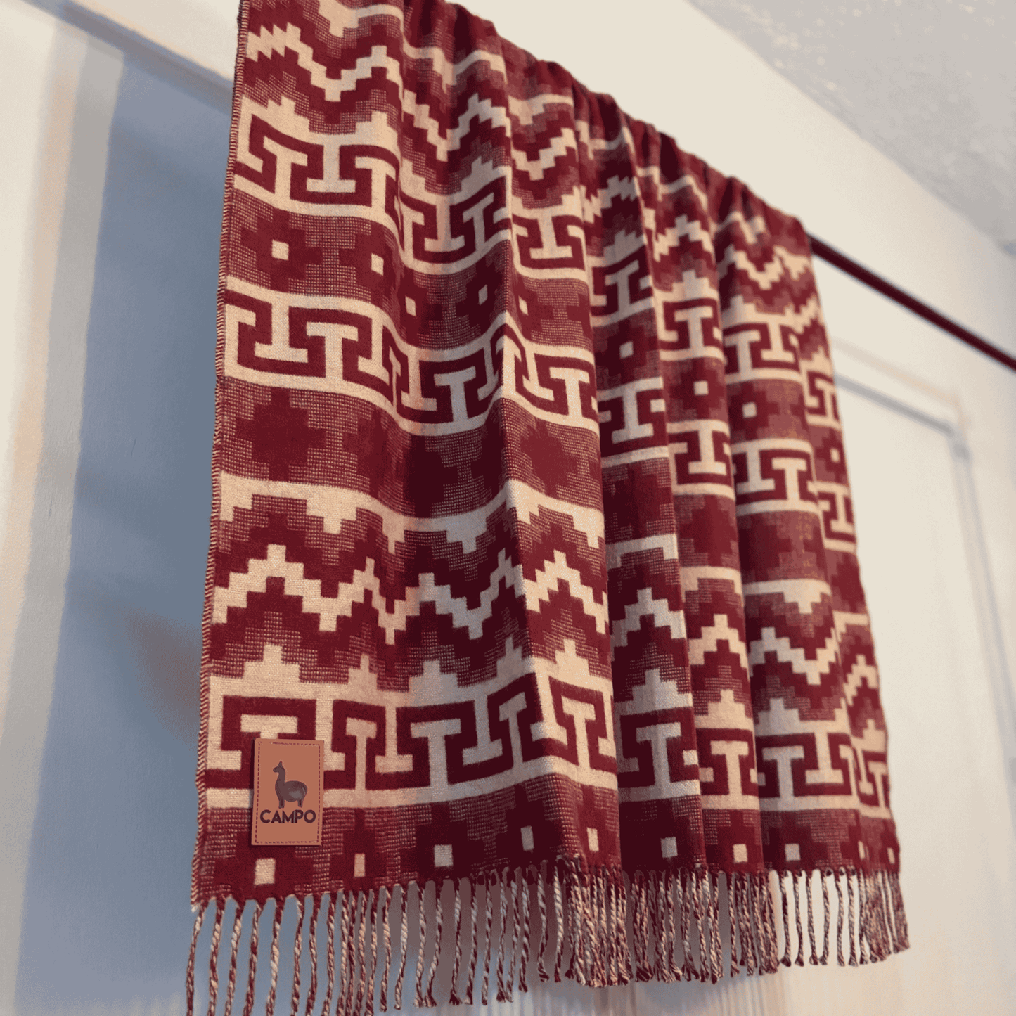 Maroon patterned scarf with fringes on a white background