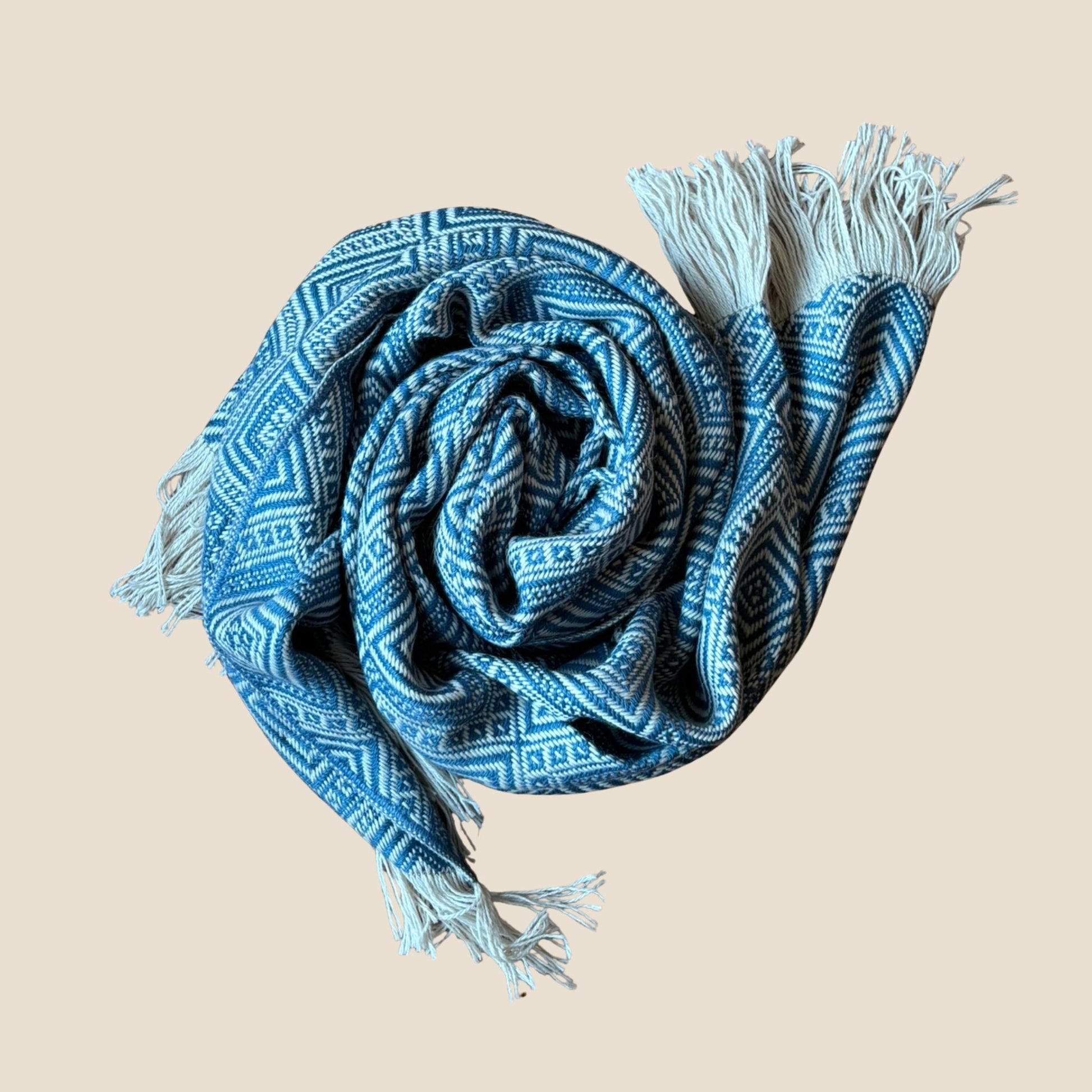 Blue patterned scarf with tassels on a beige background