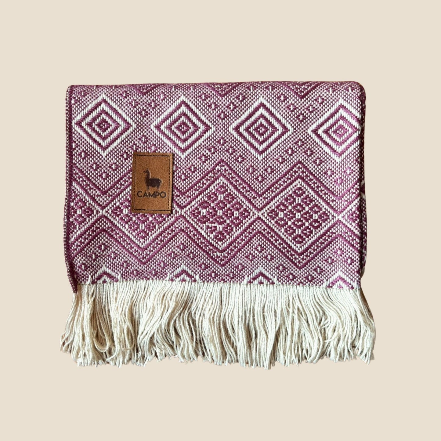 Woven blanket with geometric pattern and fringes on a beige background