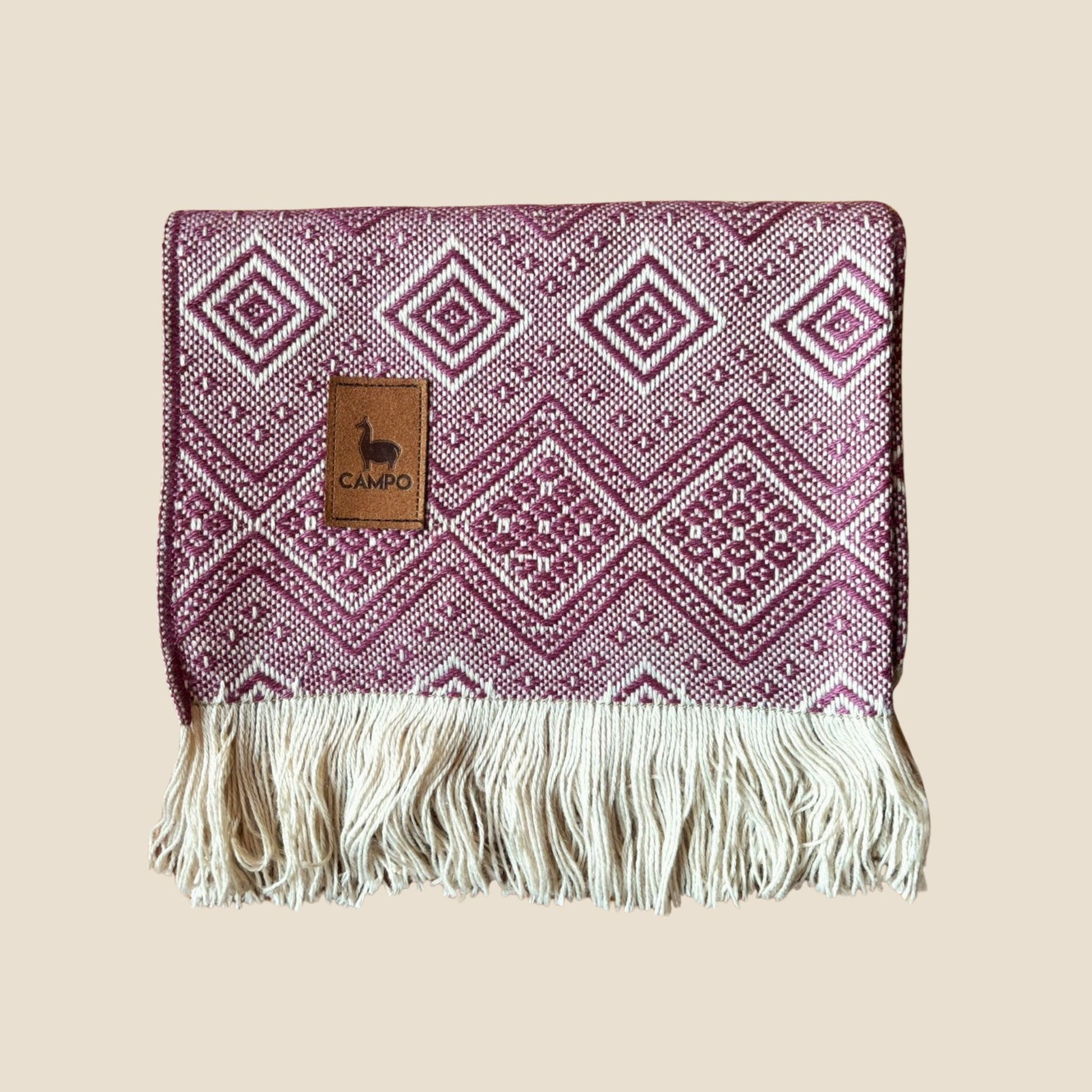Woven blanket with geometric pattern and fringes on a beige background