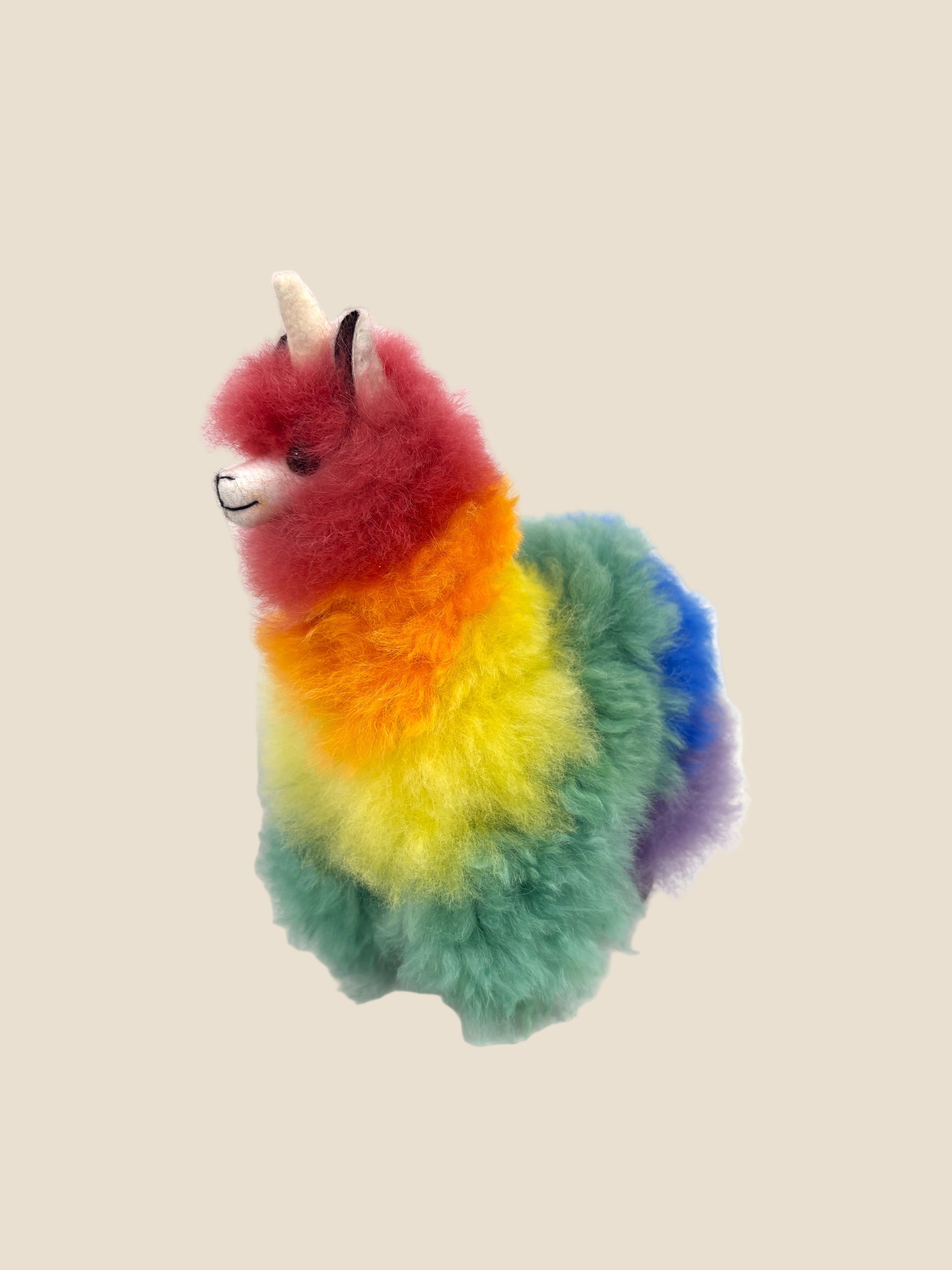 Colorful plush toy resembling a llama with a unicorn horn on a white background