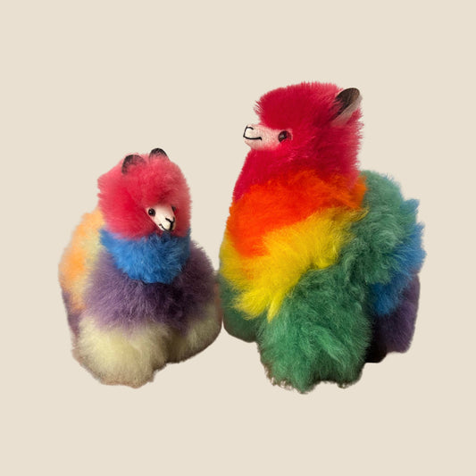 Two colorful plush toys resembling alpaca on a beige background
