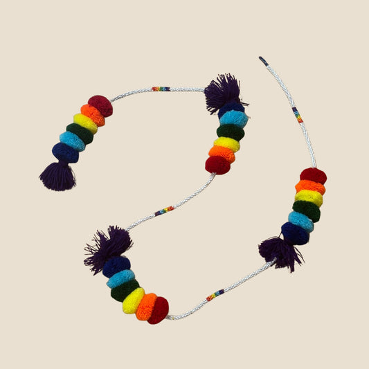 Colorful pom pom with multicolored beads and tassels on a beige background