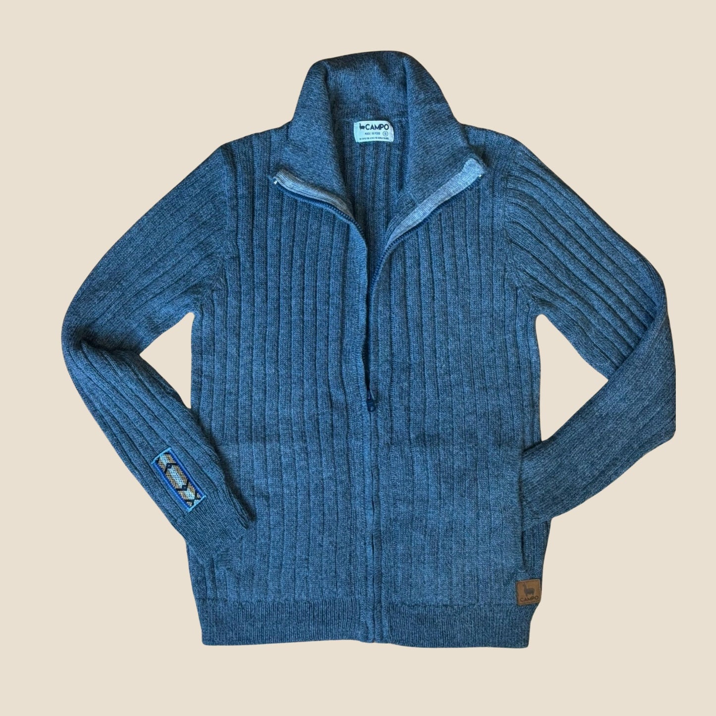 Denim ribbed sweater with a campo logo on a beige background