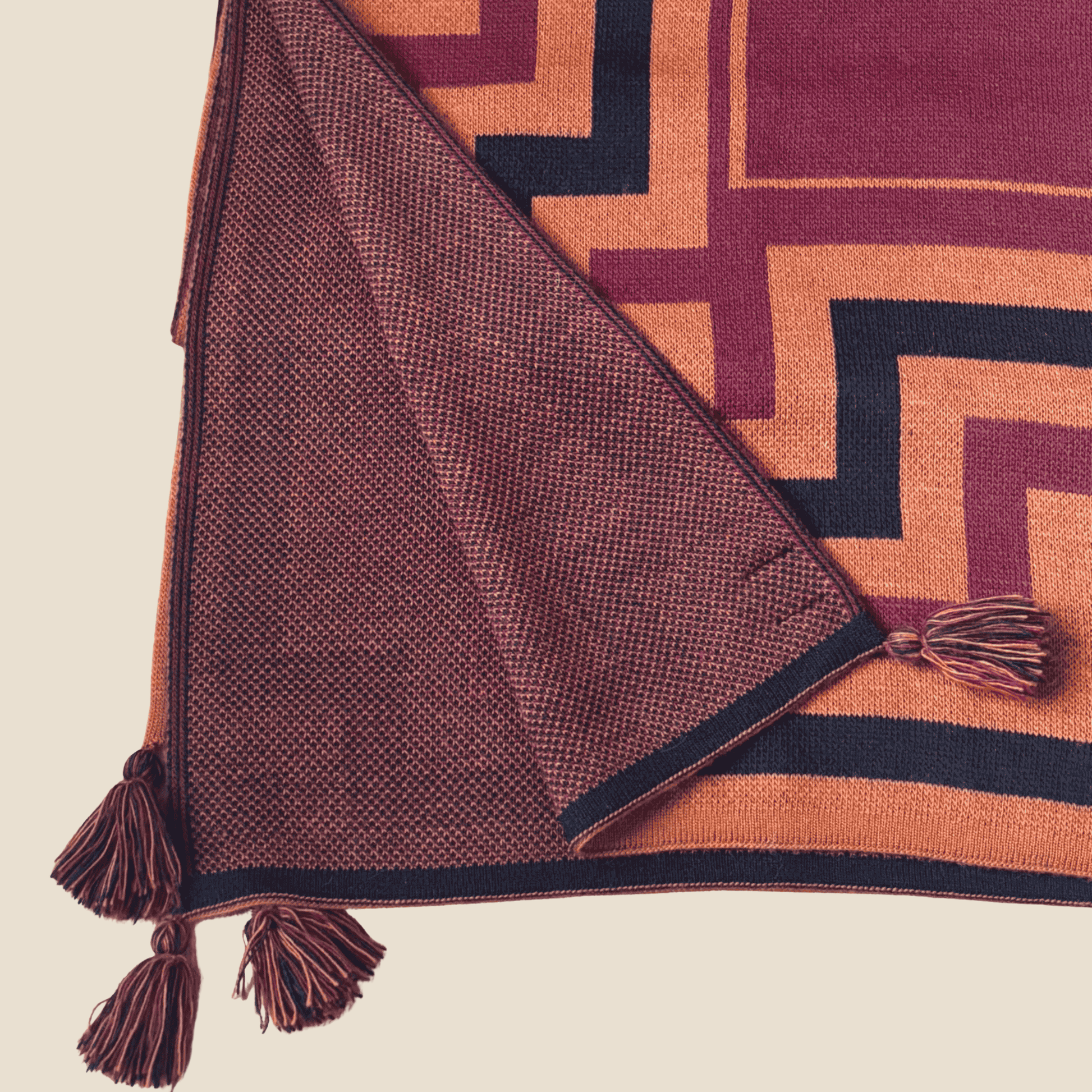 Brown textured blanket with tassels on a geometric patterned surface
