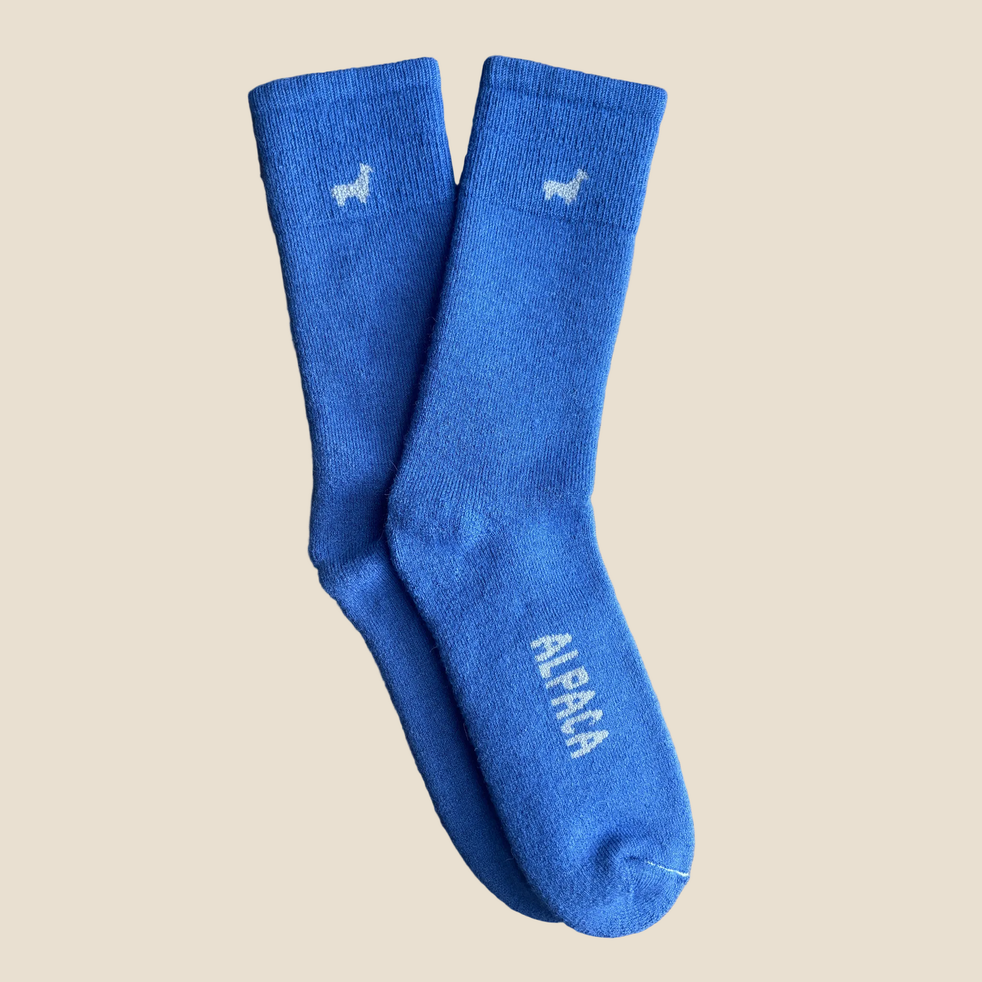 Pair of blue socks with 'Alpaca' text on a beige background