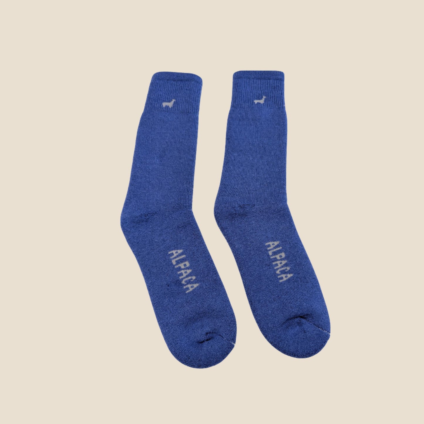 Pair of lilac socks with 'ALPACA' branding on a beige background