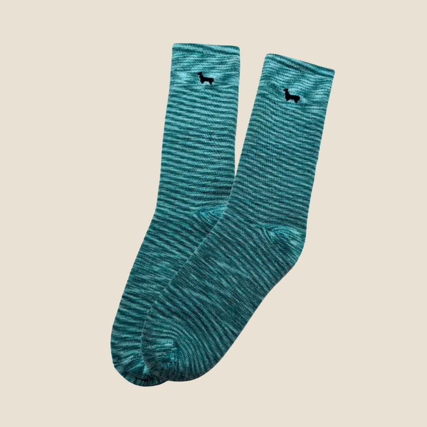 Pair of teal socks with black alpaca design on a beige background