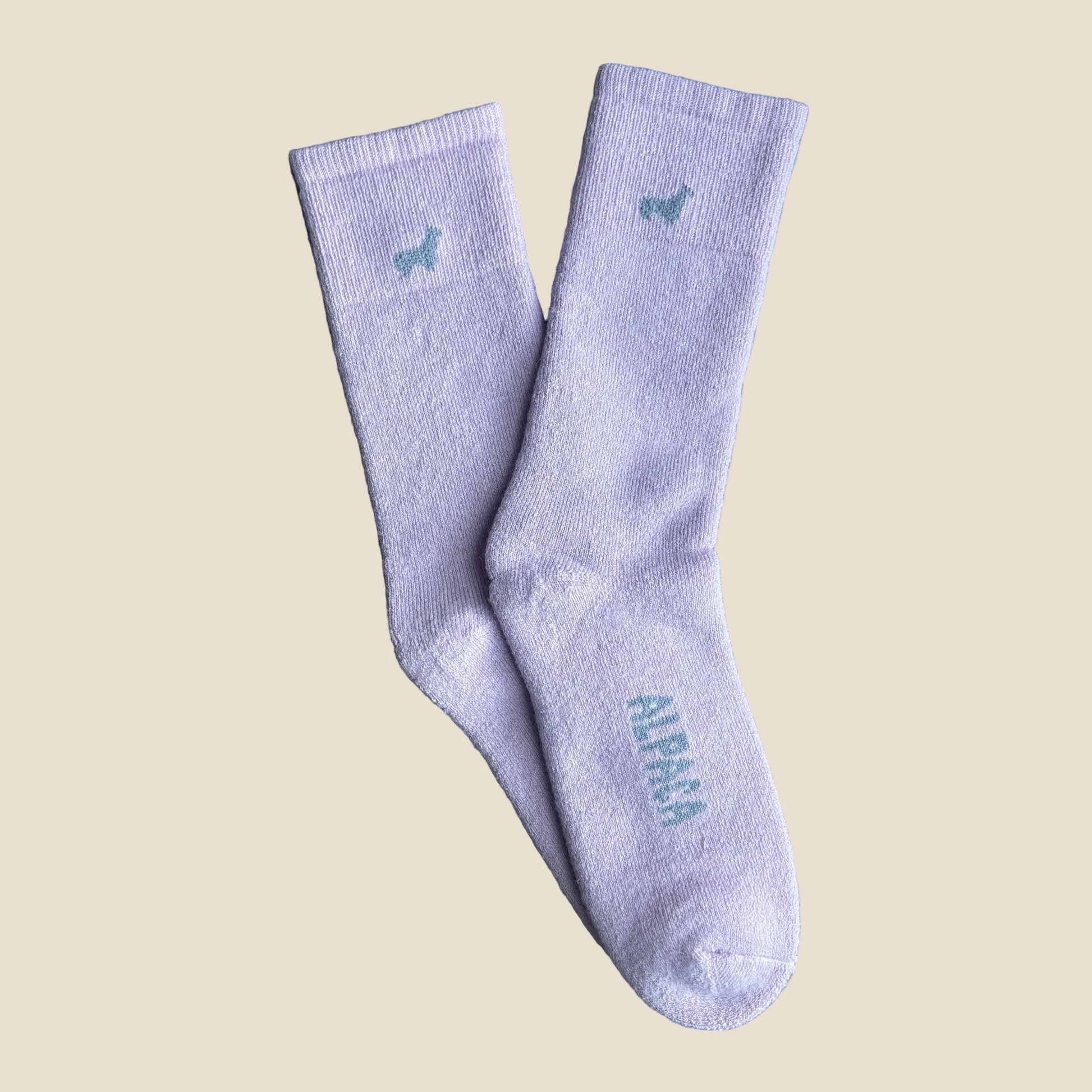 Pair of light purple socks with small logos on a beige background