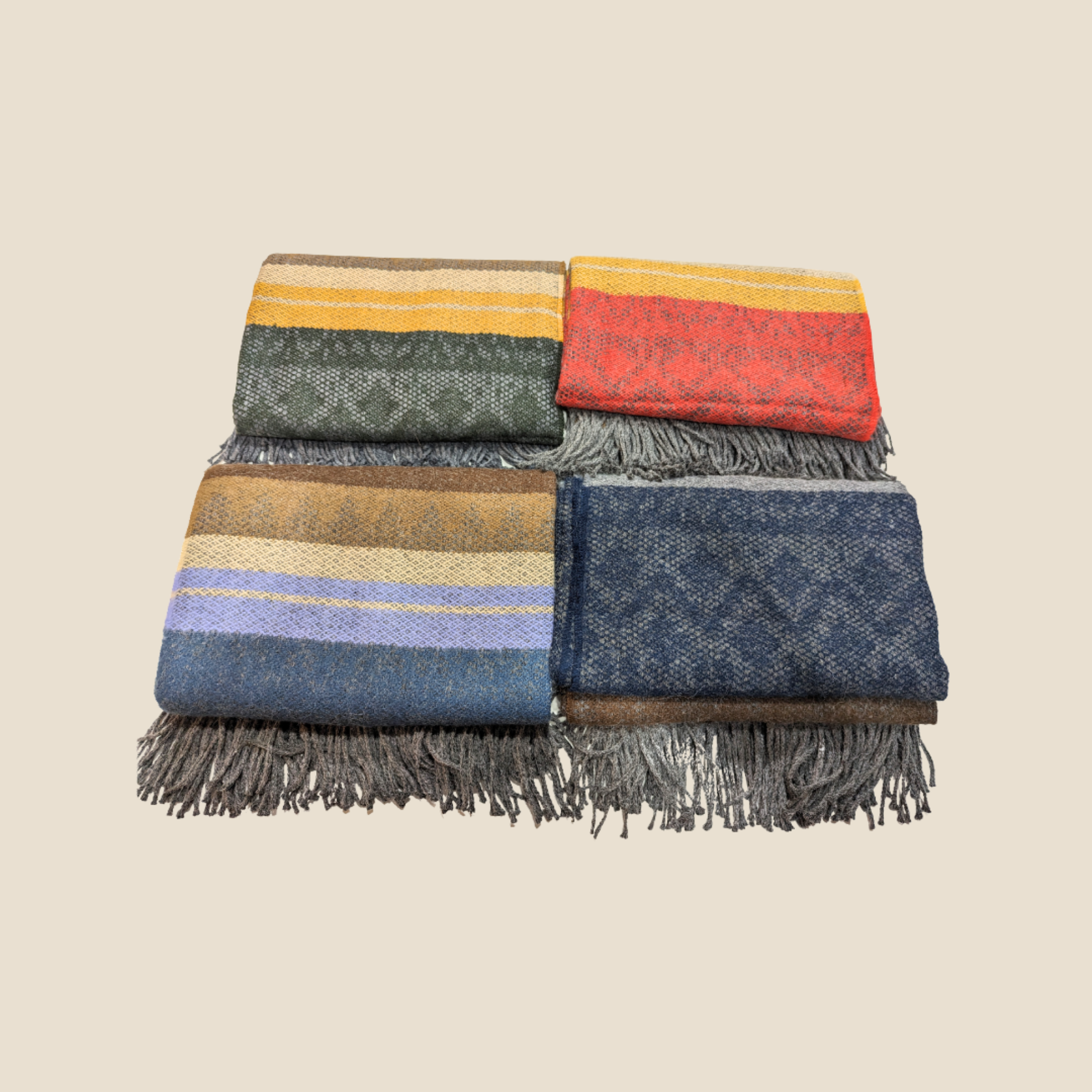 Set of colorful woven blankets with fringes on a beige background