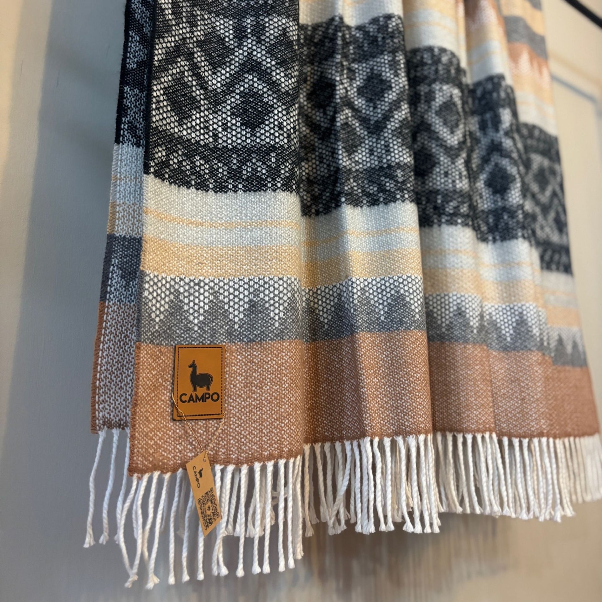 Black medley patterned scarf with fringes and a visible brand tag on a neutral background