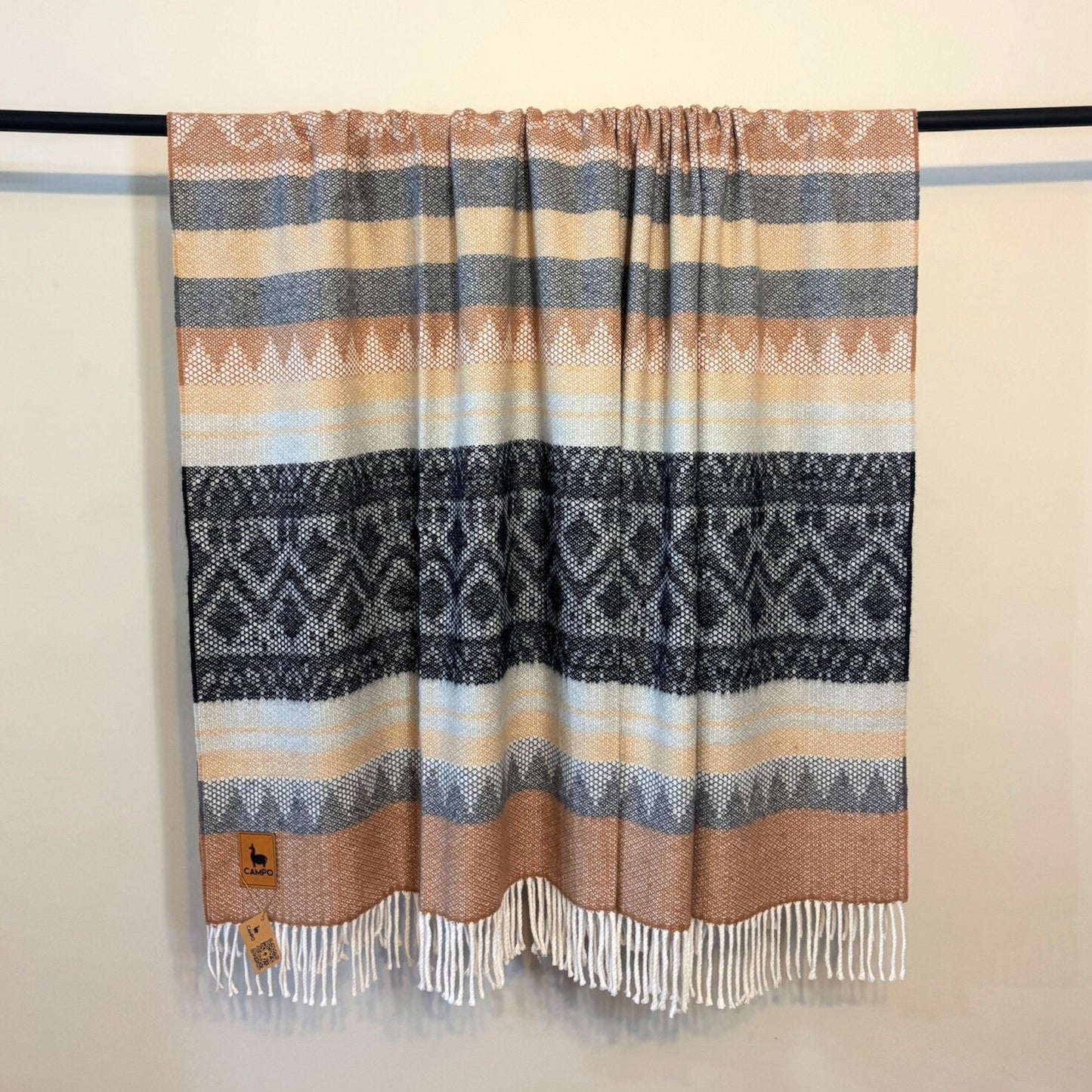 Black medley woven blanket with geometric pattern and fringes on a plain background