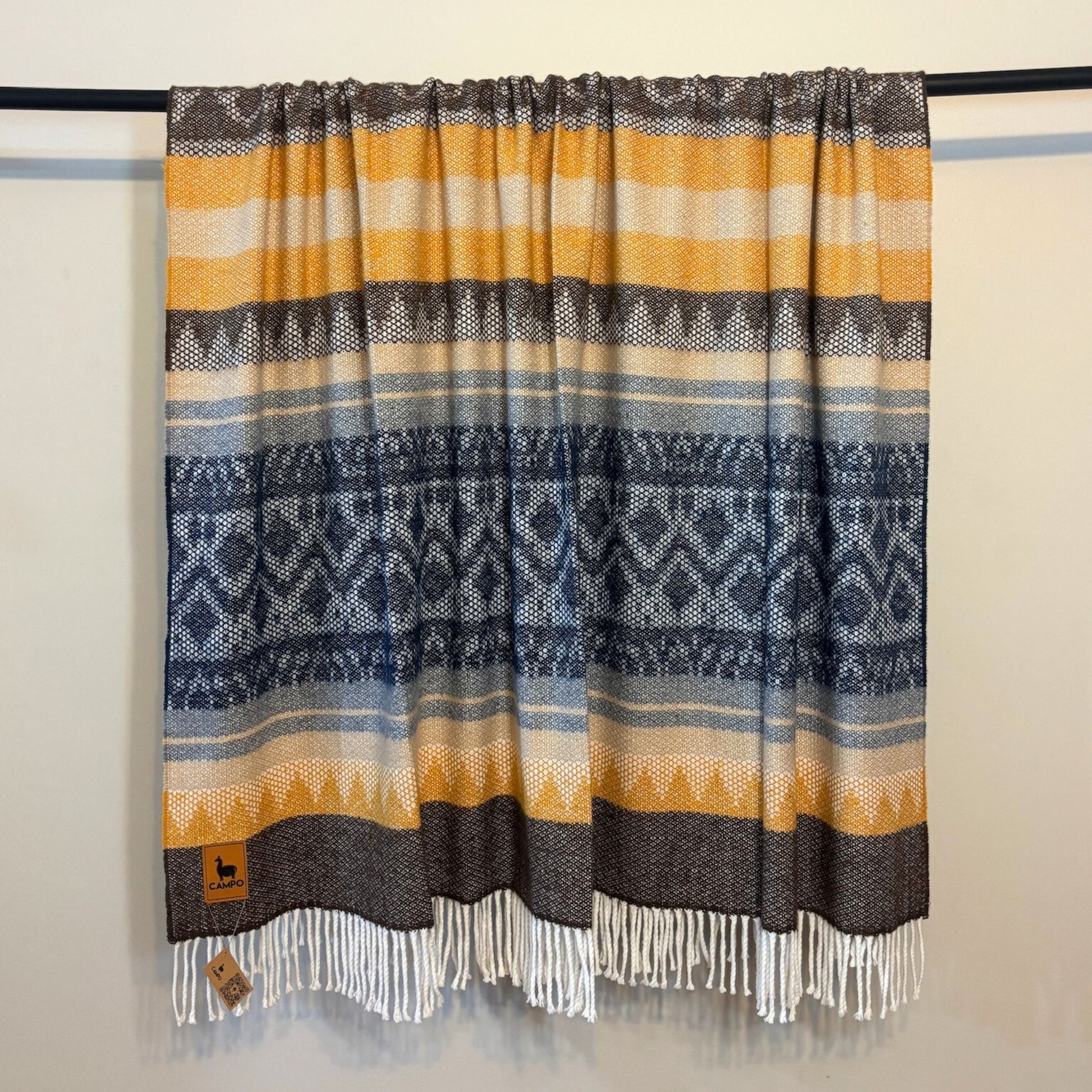 Dark  blue medley woven blanket with geometric pattern and fringes on a plain background