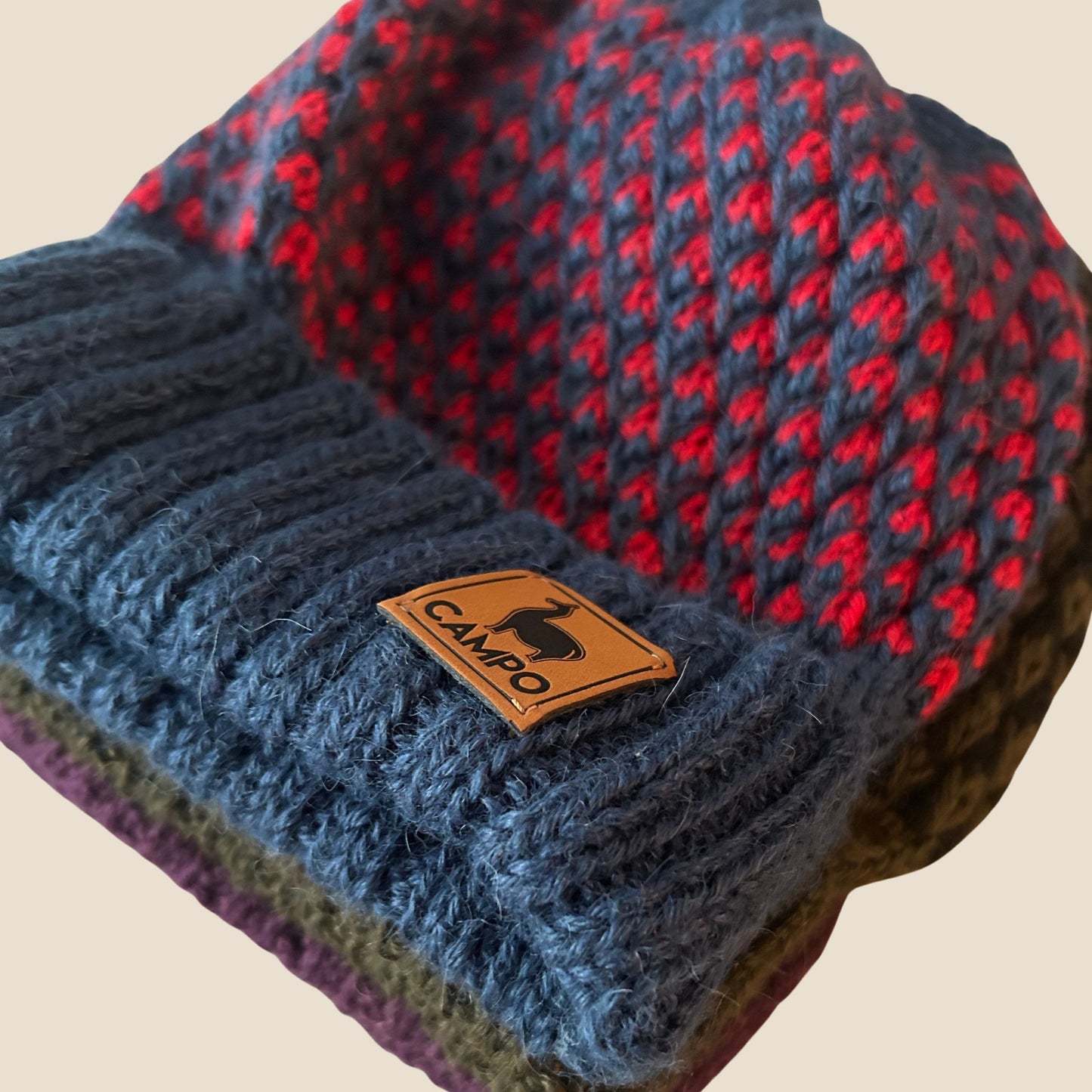 Knitted beanie with a 'Campo' label on a beige background