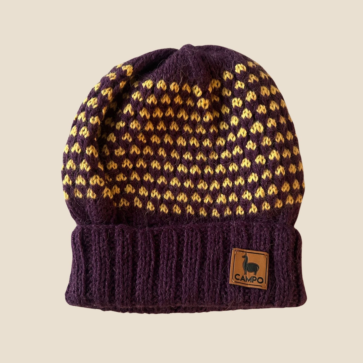 Purple knit beanie with yellow pattern and 'Campo' logo on a beige background
