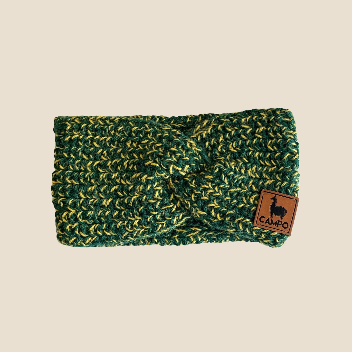 Green and gold twisted headband with a brown 'Campo' logo tag on a beige background