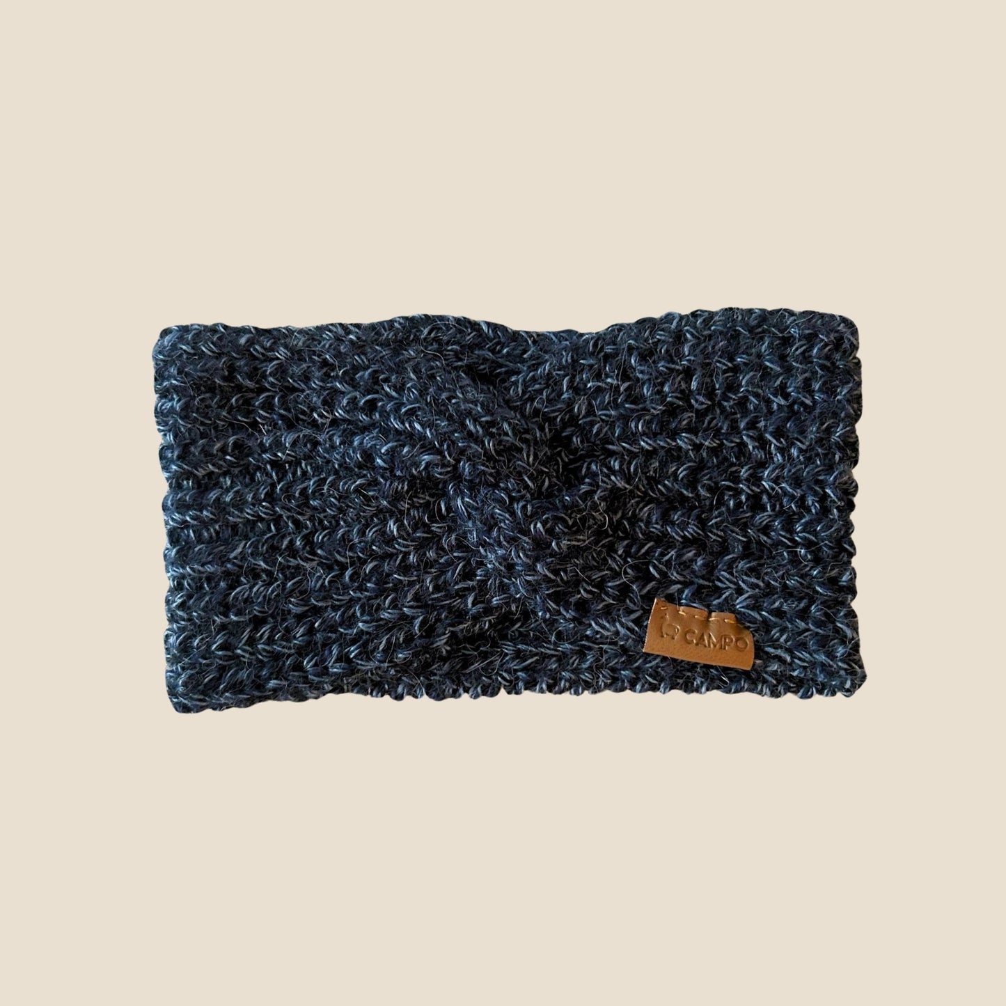 Blue twisted headband with a brand tag on a beige background
