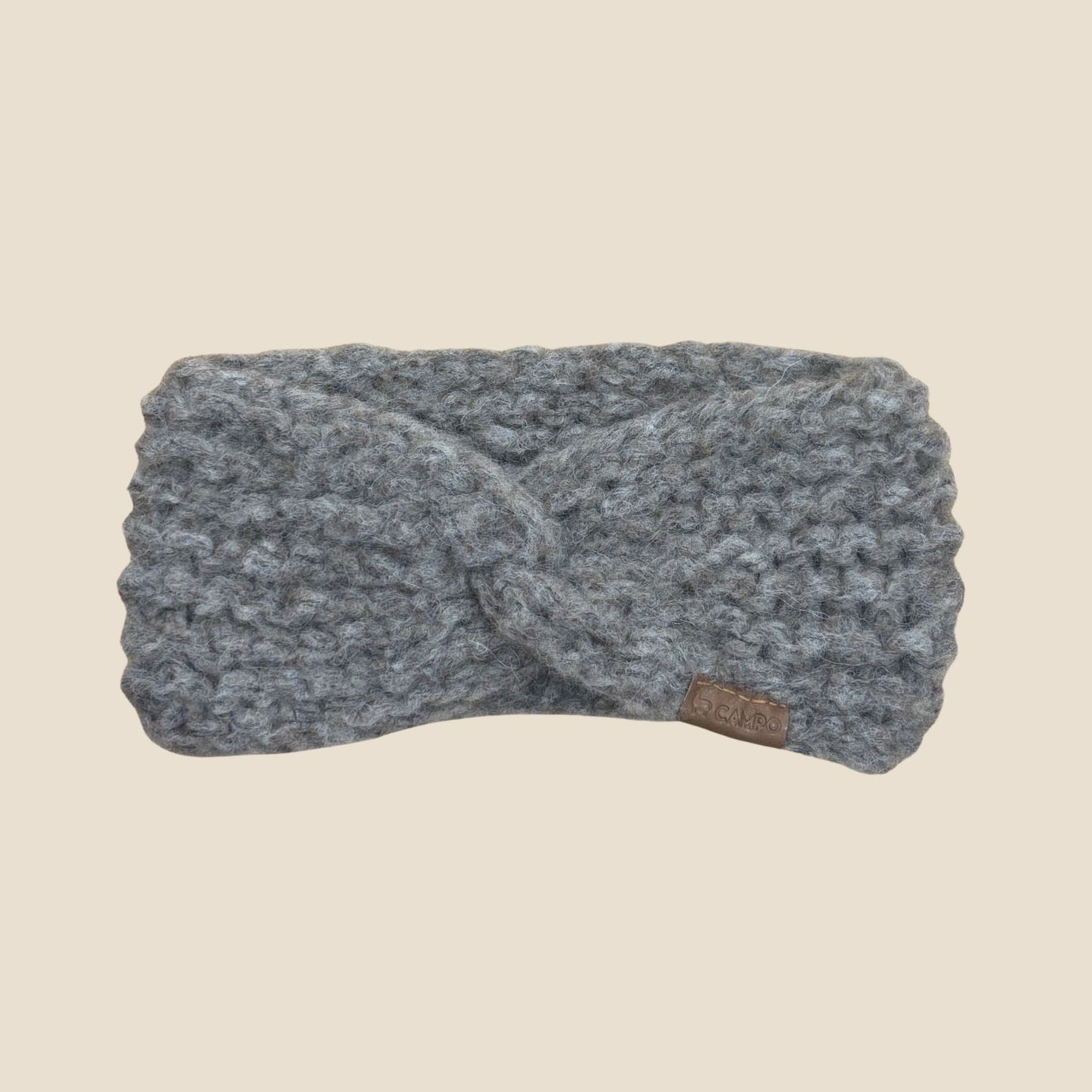 Oatmeal twisted headband with a brand tag on a beige background
