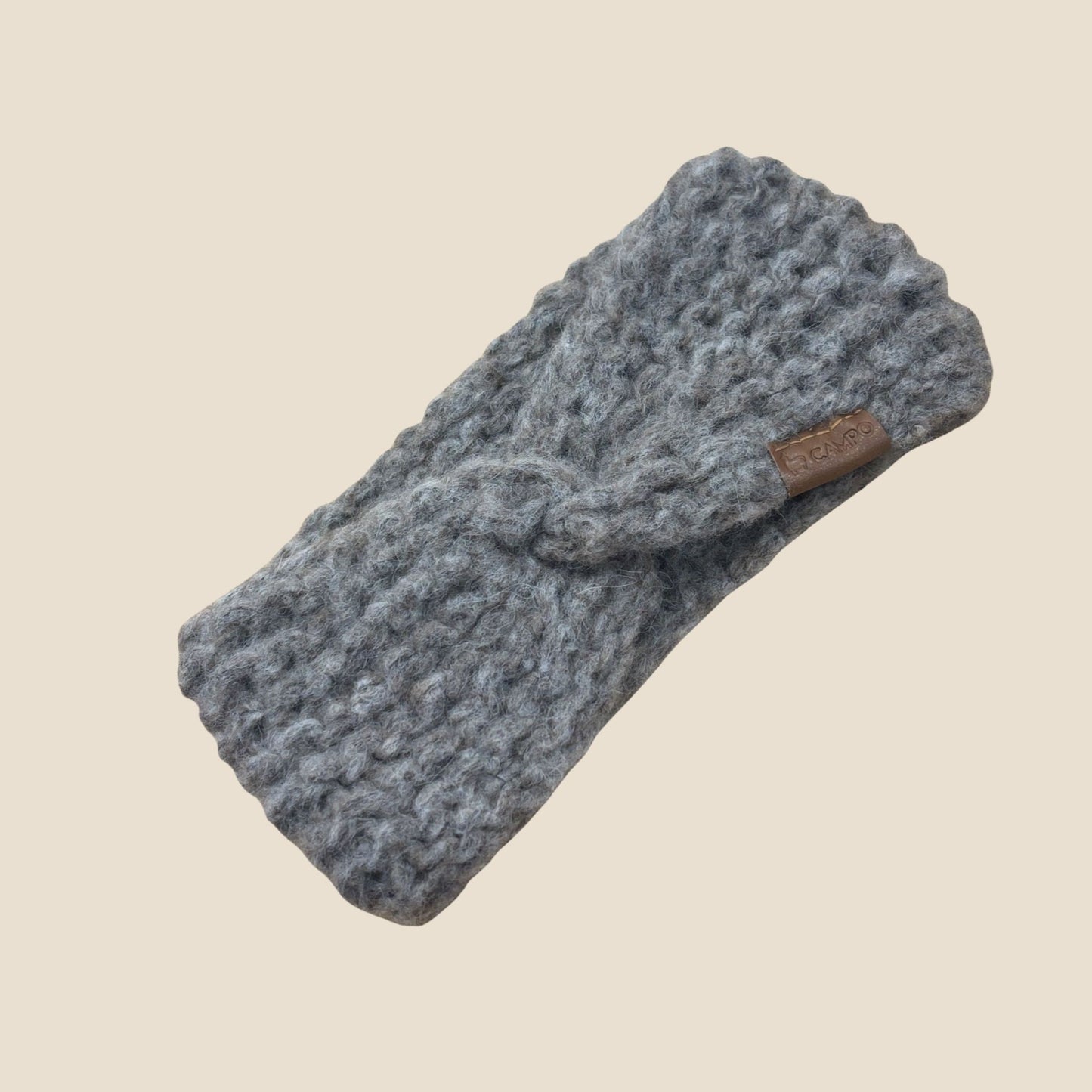 Oatmeal twisted headband with a brown label on a beige background