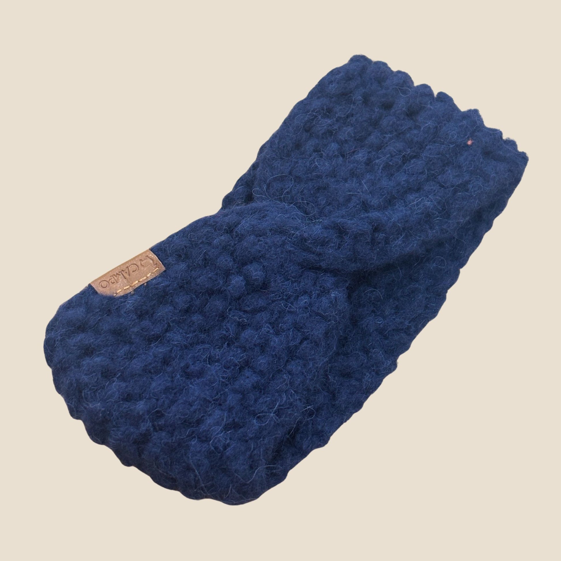 Dark blue twisted headband with a brown label on a beige background
