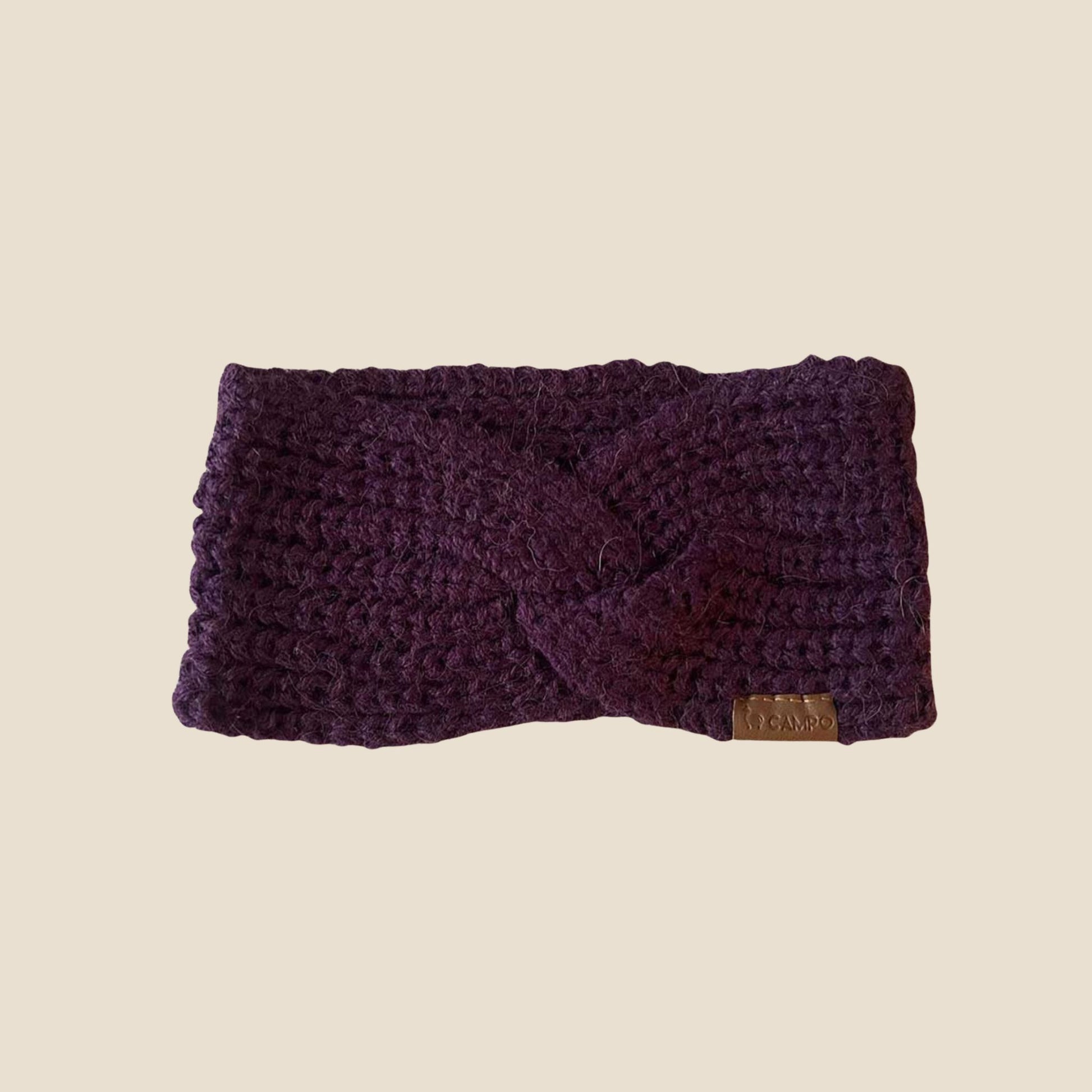Purple twisted headband with a brand label on a beige background