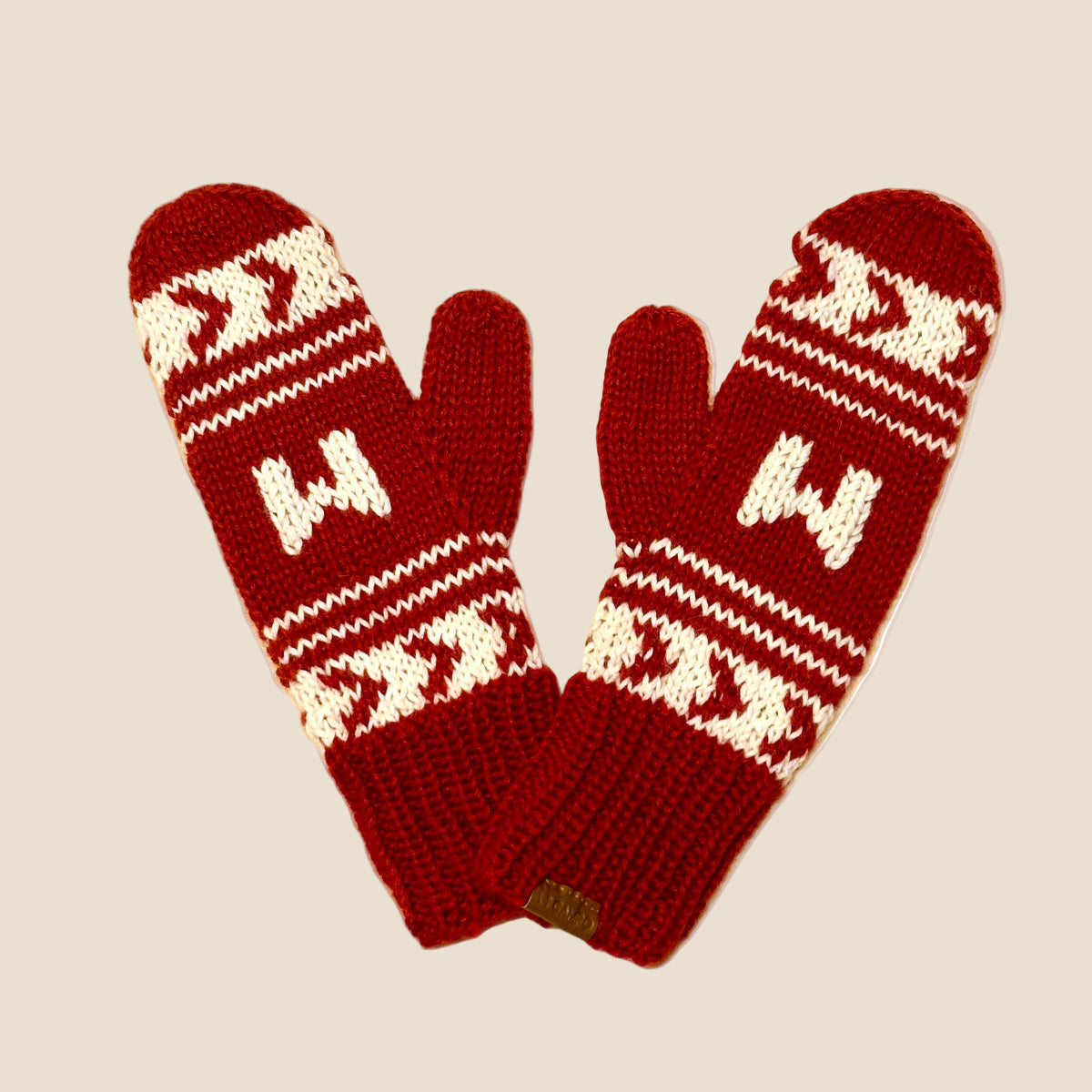 Pair of red mittens with white pattern on a beige background