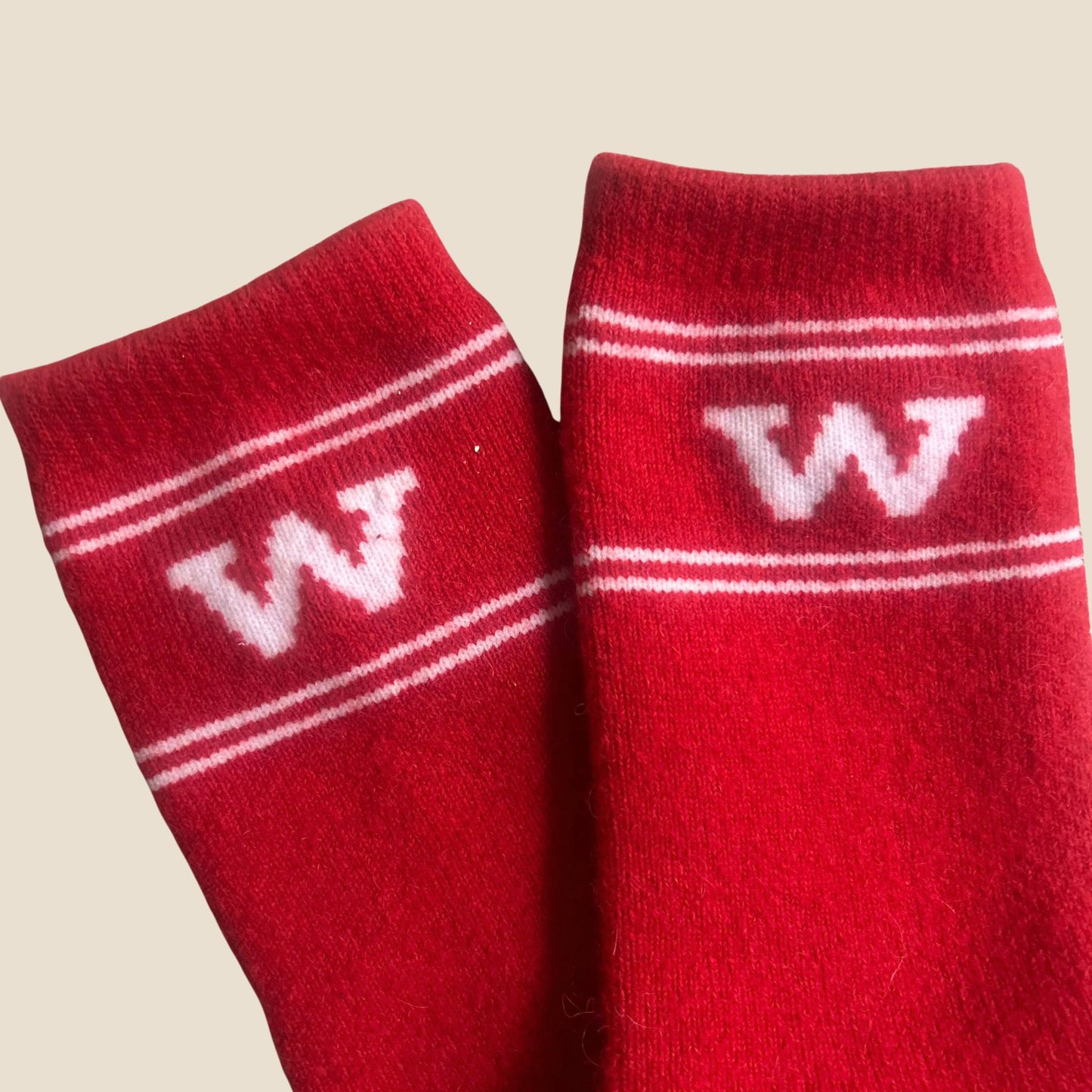 Red socks with white stripes and letter 'W' on a beige background