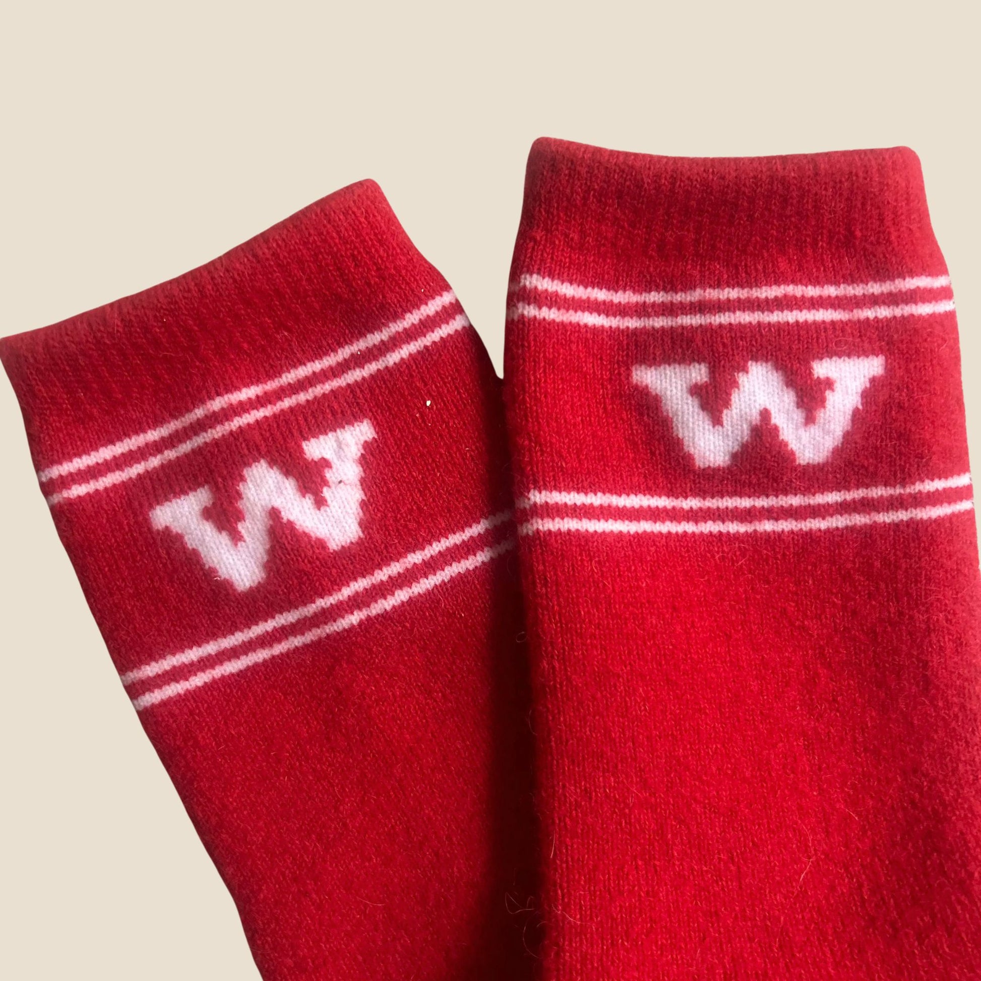 Red socks with white stripes and letter 'W' on a beige background