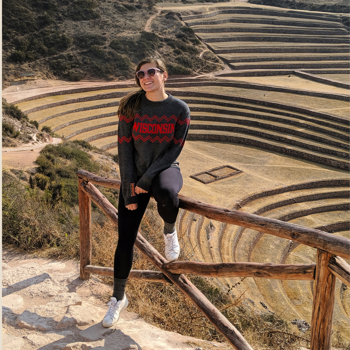 Person standing on a wooden railing with terraced fields in the background
