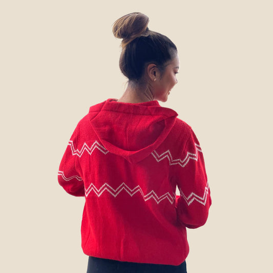 Person wearing a red hoodie with white patterns on a beige background