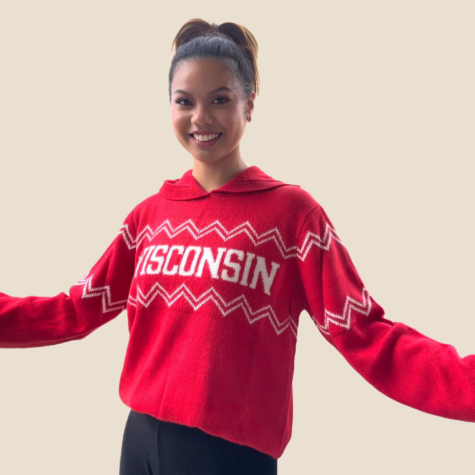Person wearing a red 'Wisconsin' sweater against a plain background