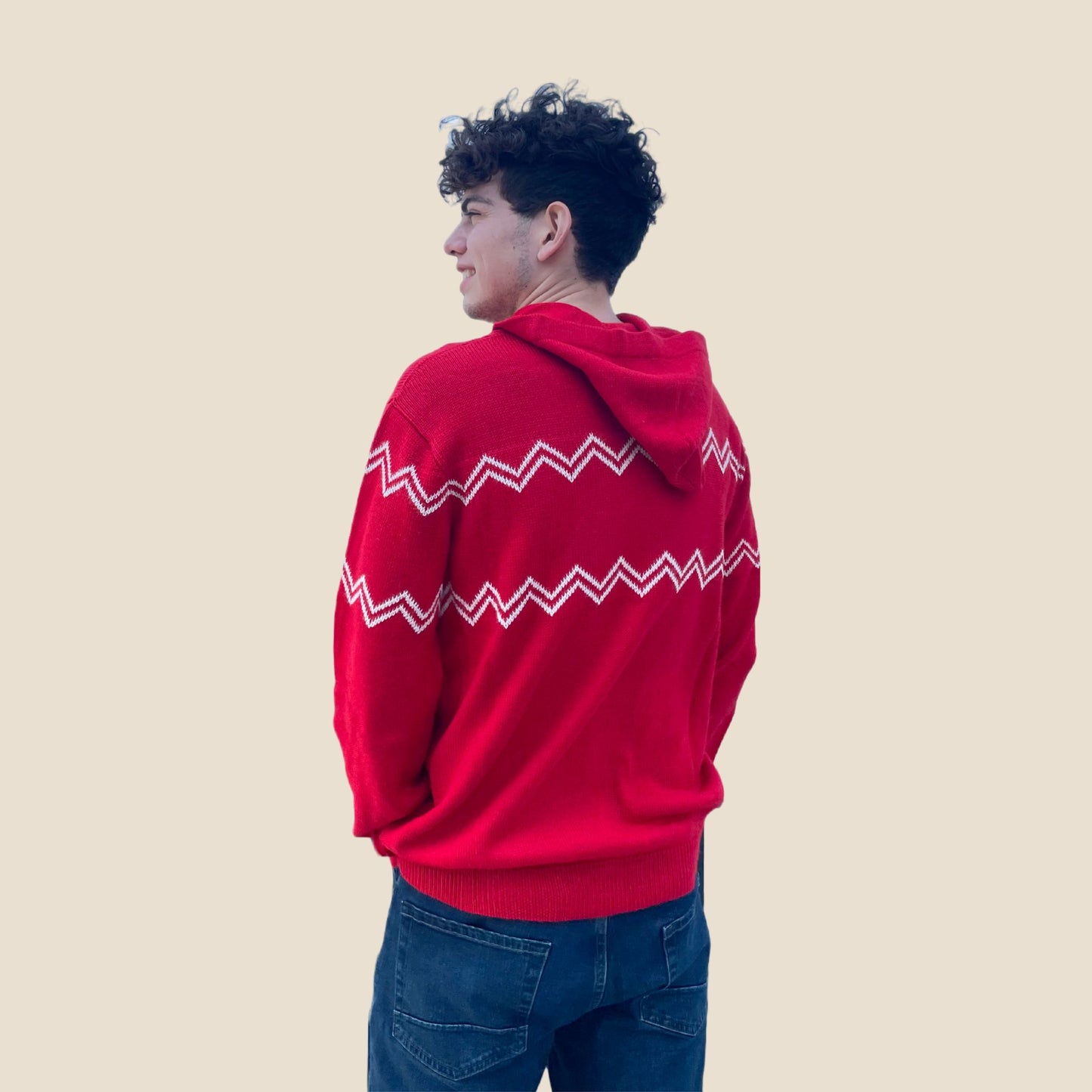Person wearing a red hoodie with white patterns on a beige background