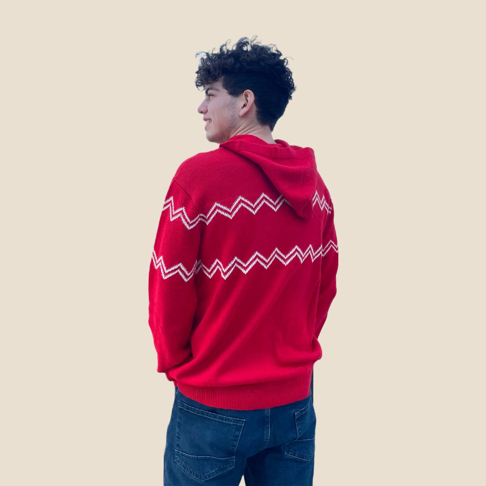 Person wearing a red hoodie with white patterns on a beige background