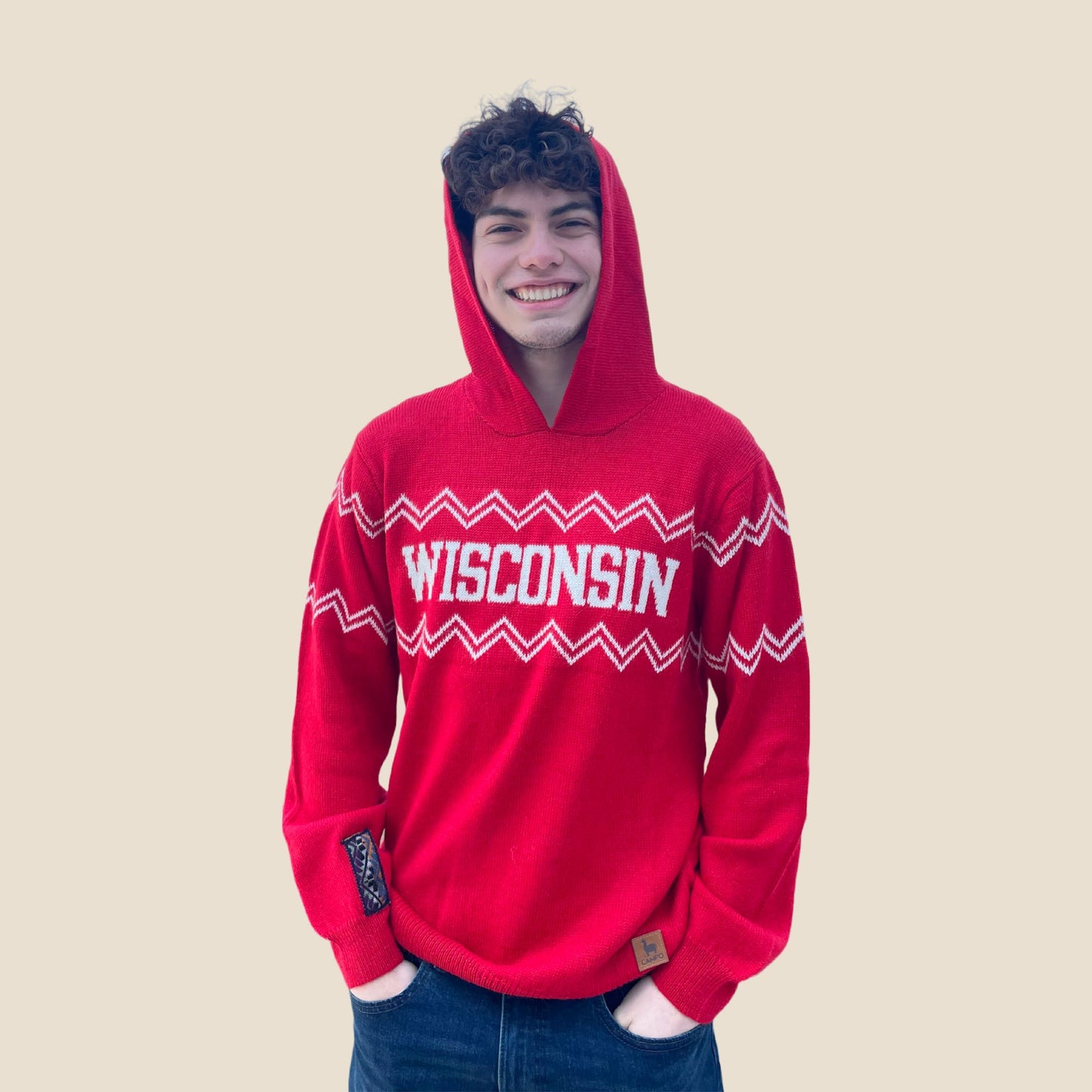 Person wearing a red 'Wisconsin' hoodie on a beige background