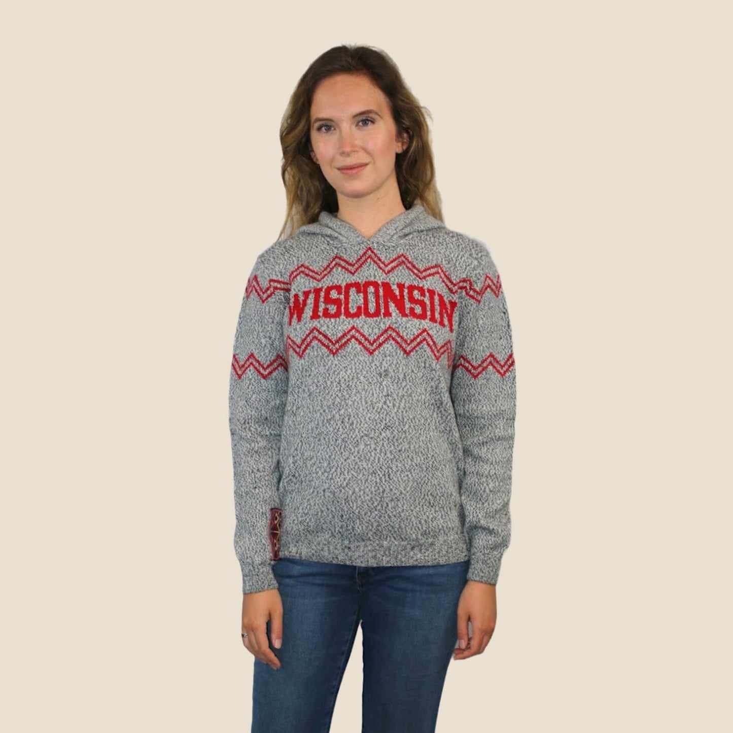 Person wearing a gray hoodie with 'Wisconsin' design on a beige background
