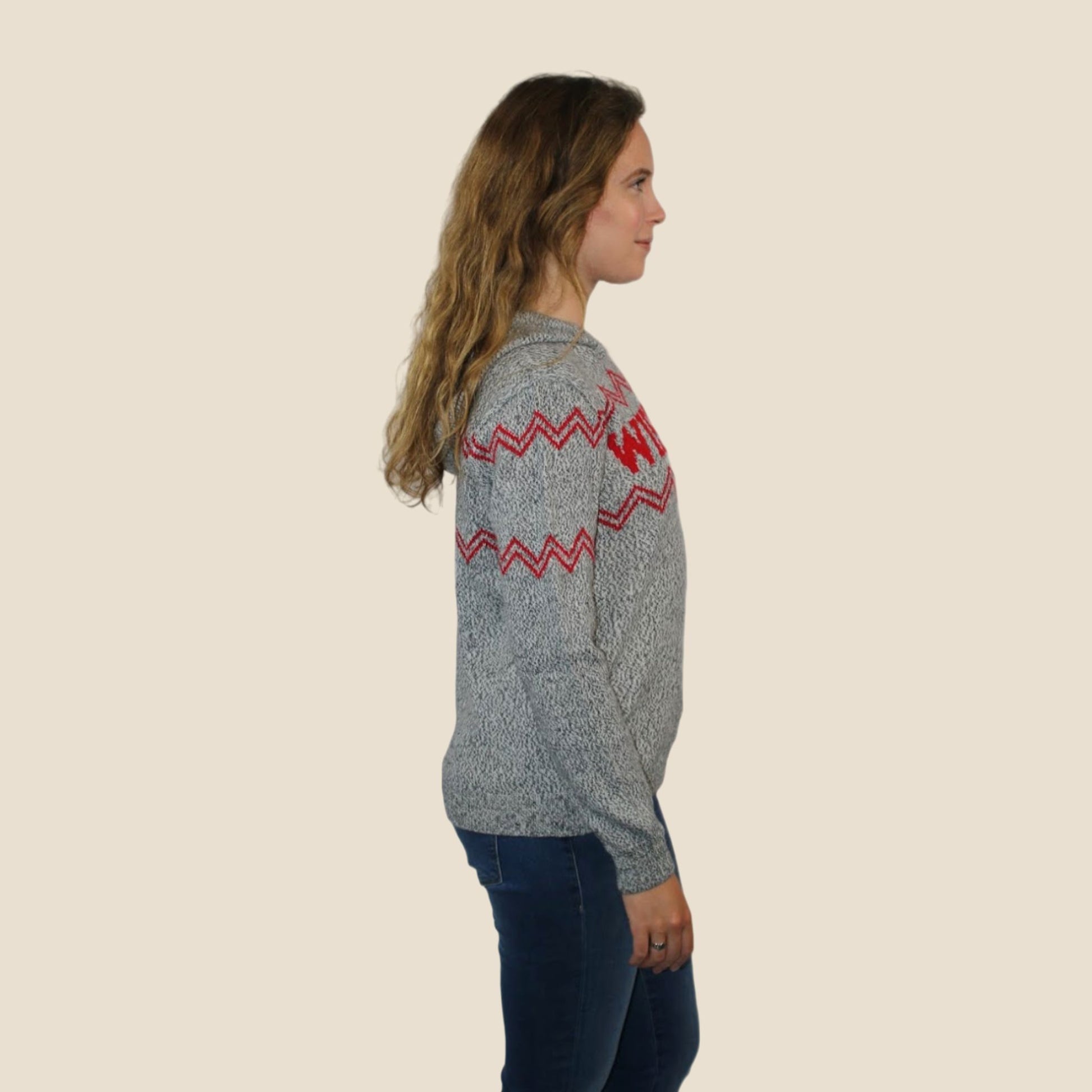 Woman wearing a gray sweater with red patterns on a beige background