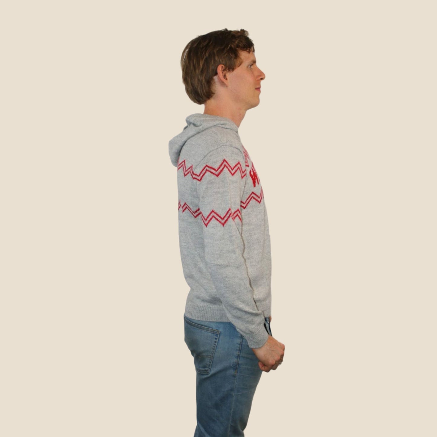Person wearing a gray hoodie with red zigzag pattern on a beige background