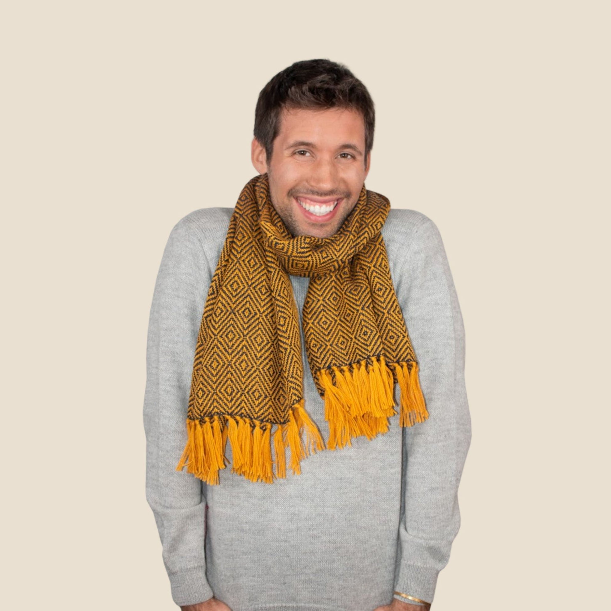 Man wearing a blue and yellow pattern scarf with geometric pattern on a beige background