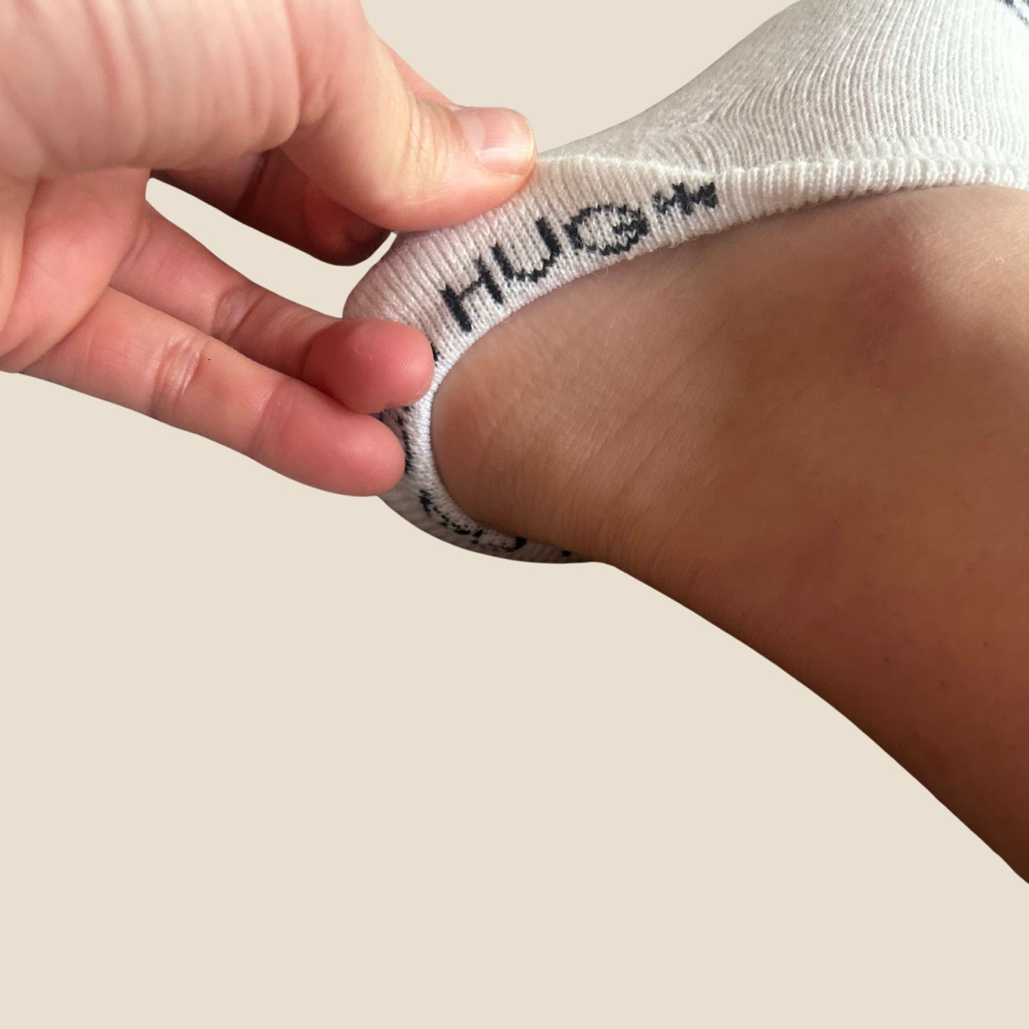 Person wearing a white sock with 'HUG' on a neutral background