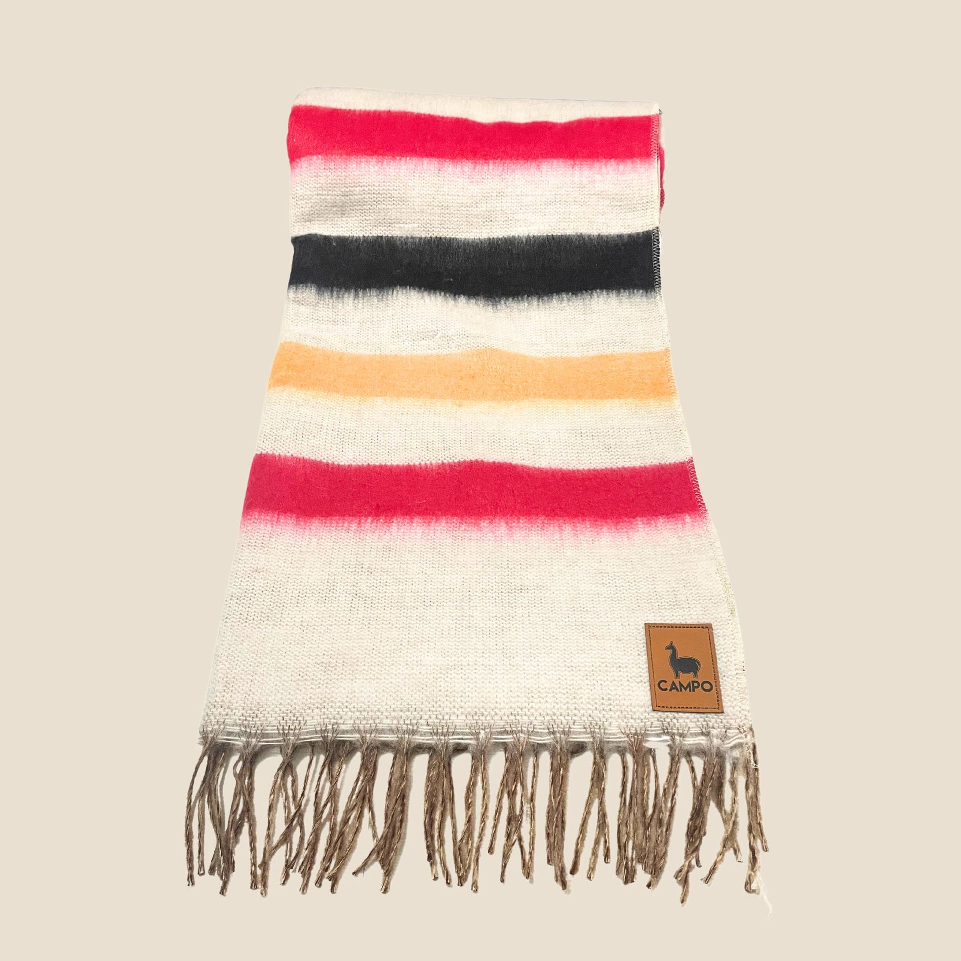 Striped blanket with fringes and a brand label on a beige background