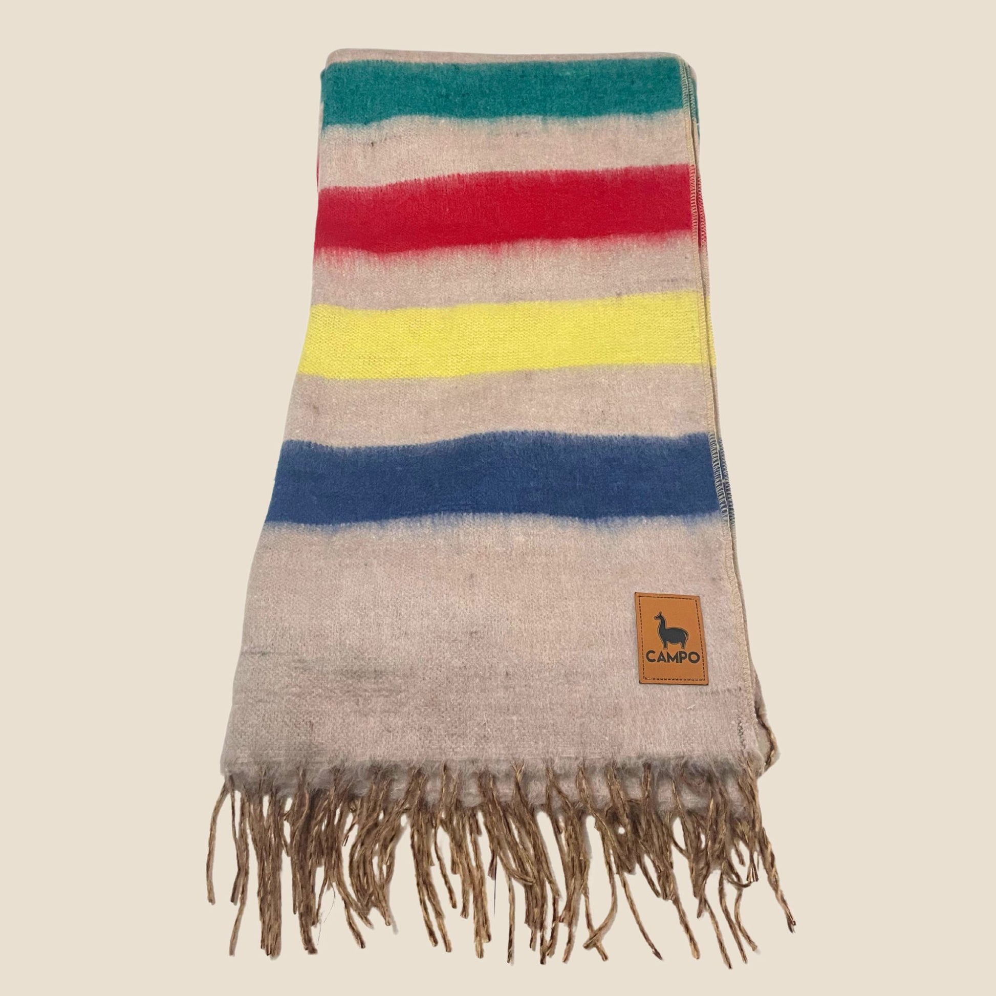 Striped blanket with fringes and a brand logo on a beige background