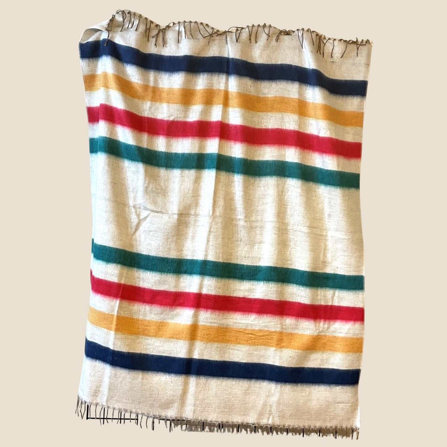 Striped blanket with red, blue, and yellow stripes on a beige background