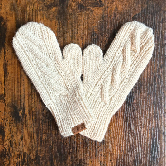 Pair of beige knitted mittens on a wooden surface