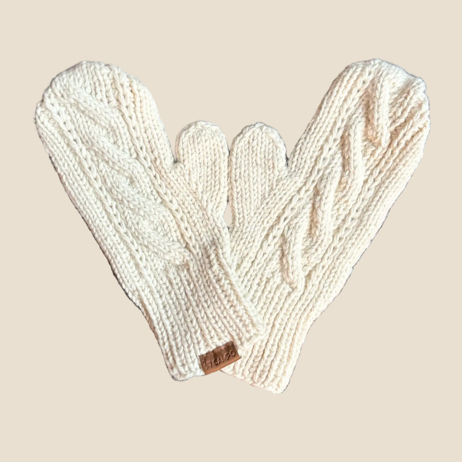 Pair of beige knitted mittens on a wooden surface