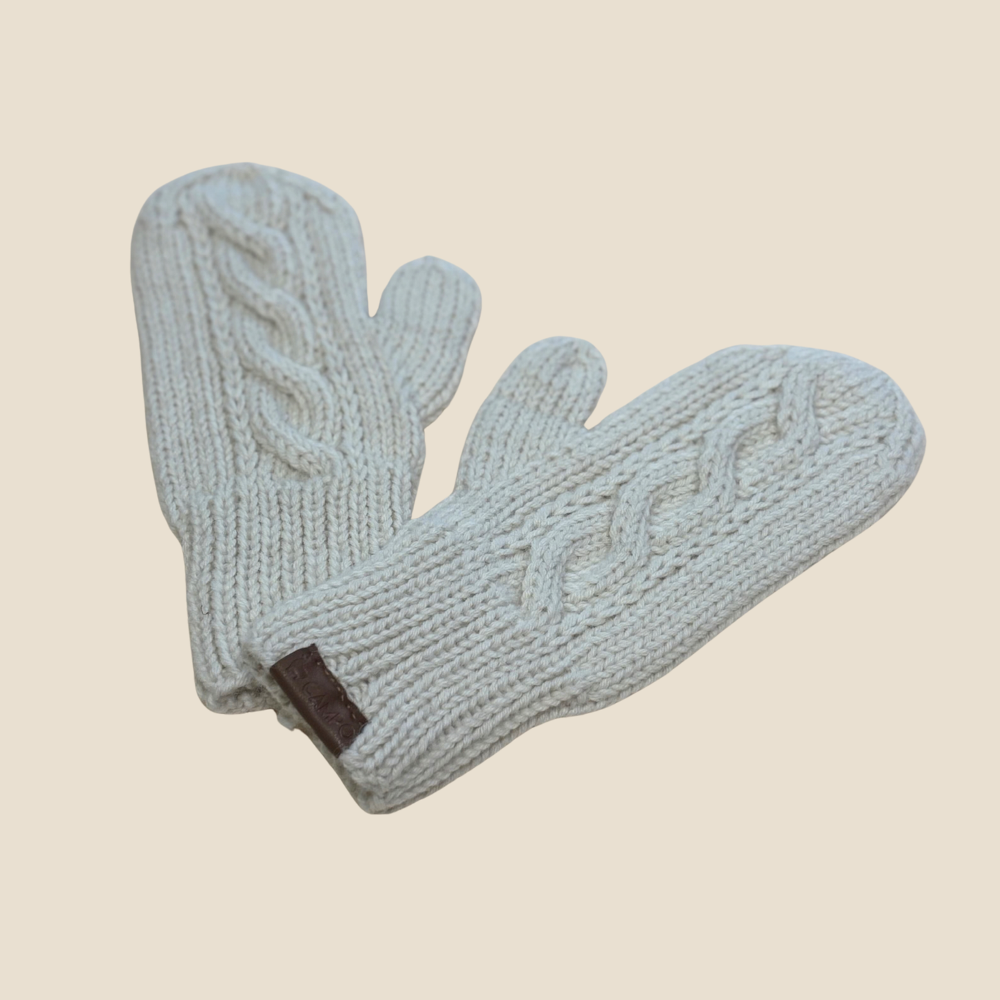 Pair of white knitted mittens on a beige background