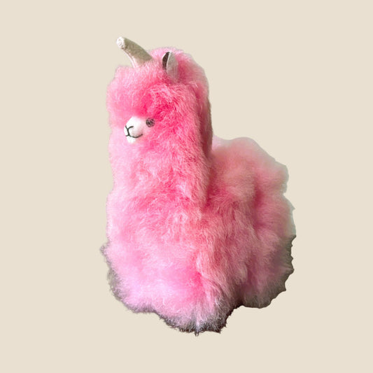 Pink plush toy resembling a alpaca on a beige background
