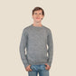 Man wearing a salt and pepper sweater and blue jeans against a beige background
