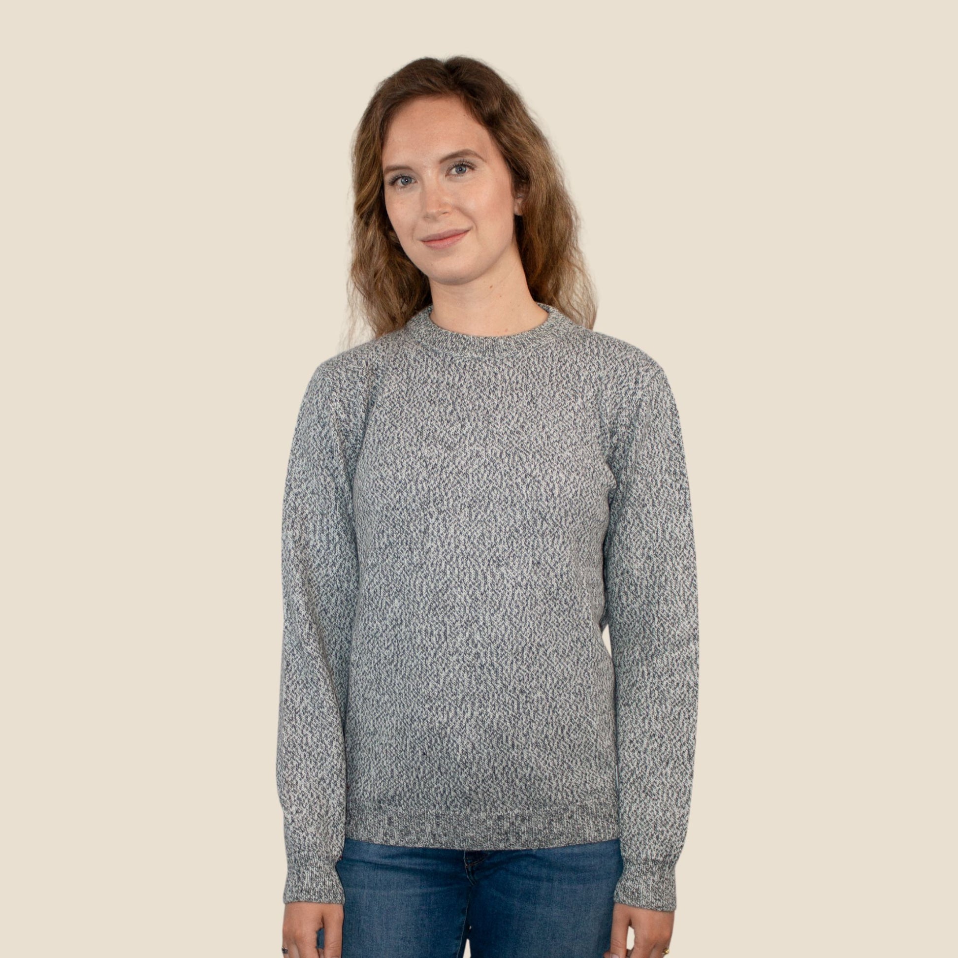 Woman wearing a salt and pepper patterned sweater against a beige background